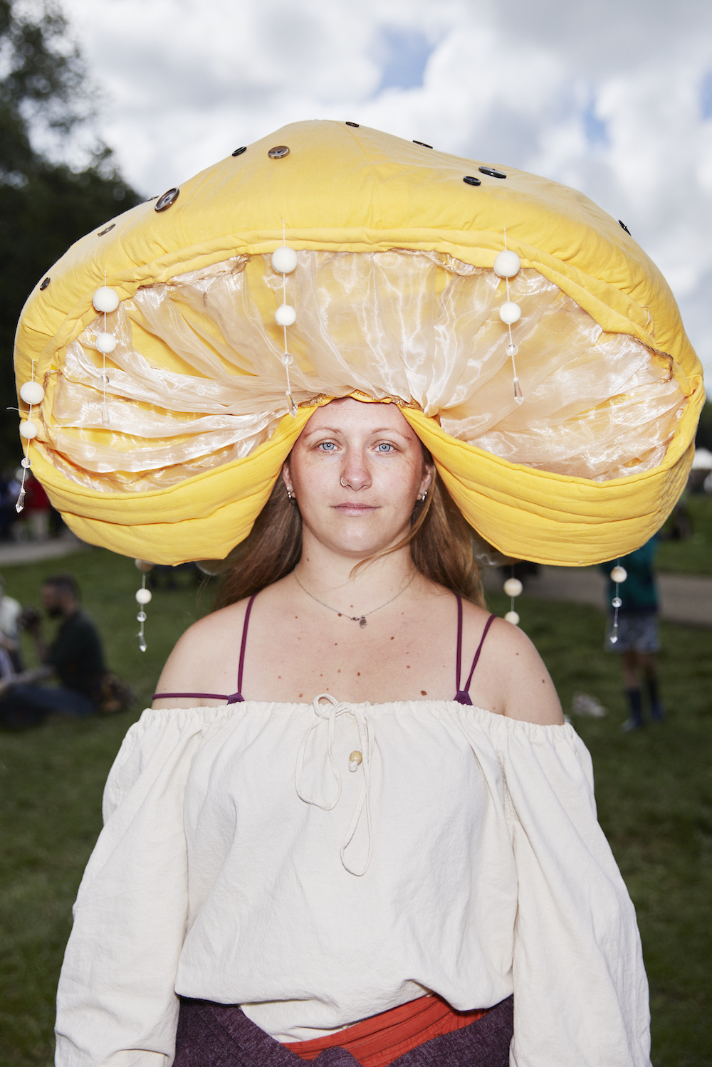 Eine Frau mit einem großen Pilzhut und weißem Oberteil