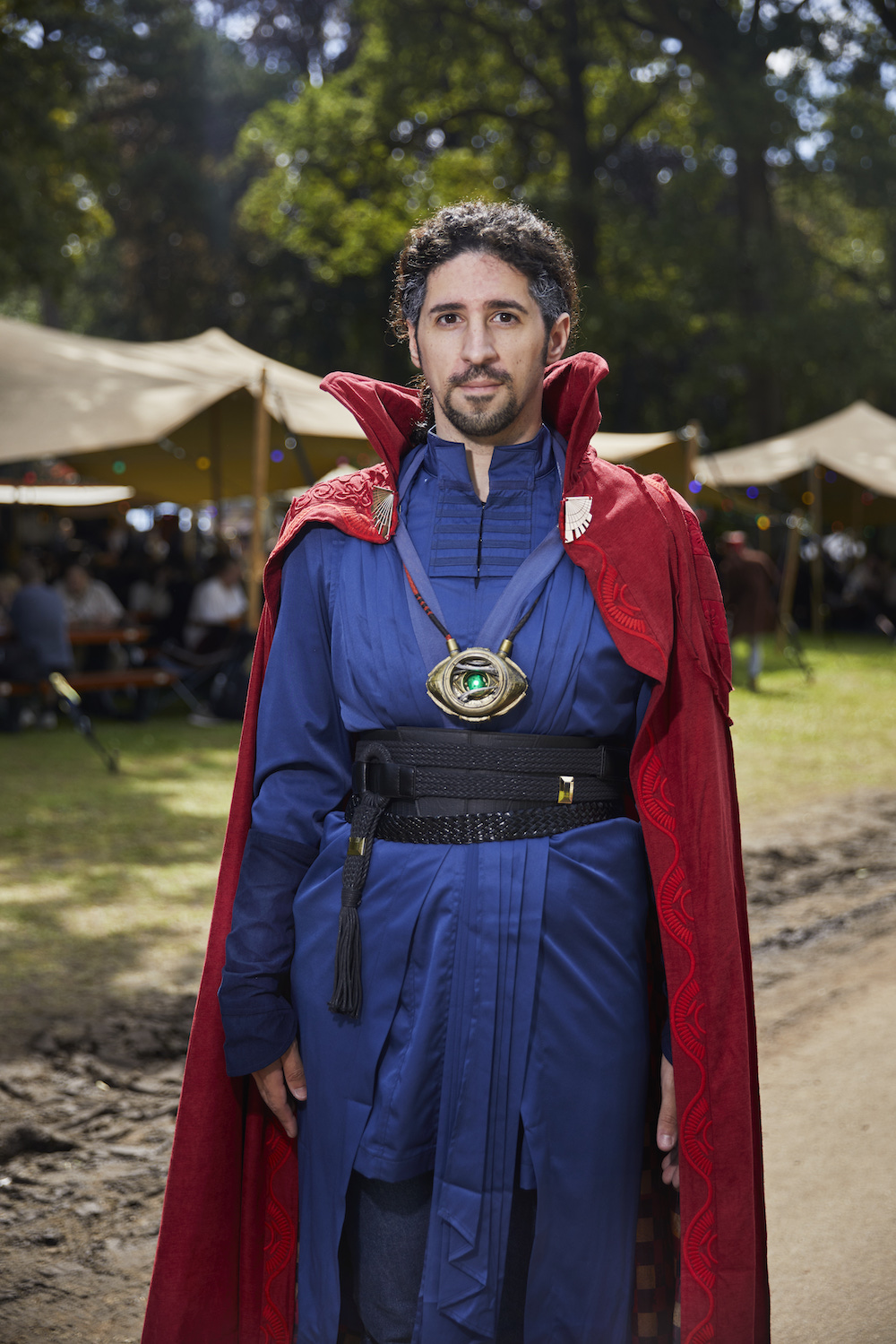 Ein Mann mit einem roten Cape, einem blauen Anzug und einem großen Amulet 