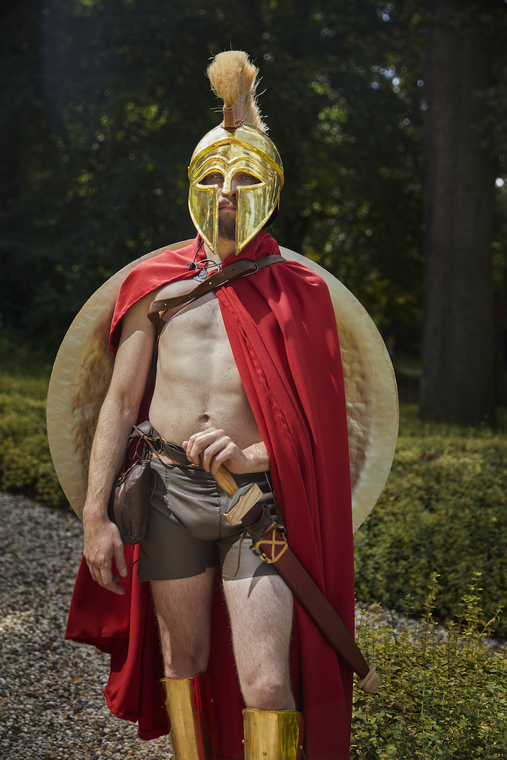 Ein Mann in einem Spartaner-Outfit mit Helm und Schild auf dem Rücken