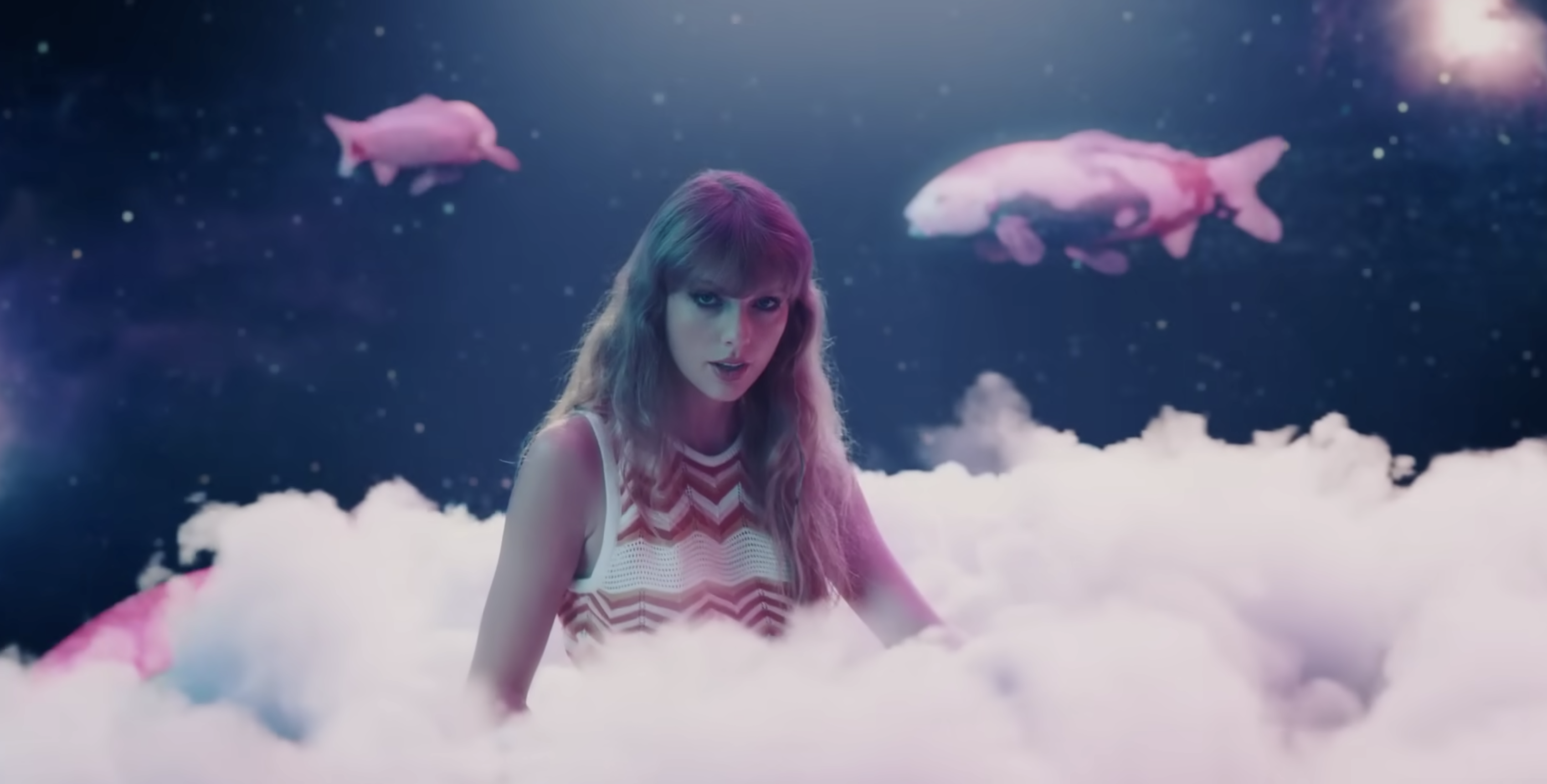 Taylor Swift sitzt auf einer Wolke. Im Himmel über sie herum schwimmen Koi Karpfen