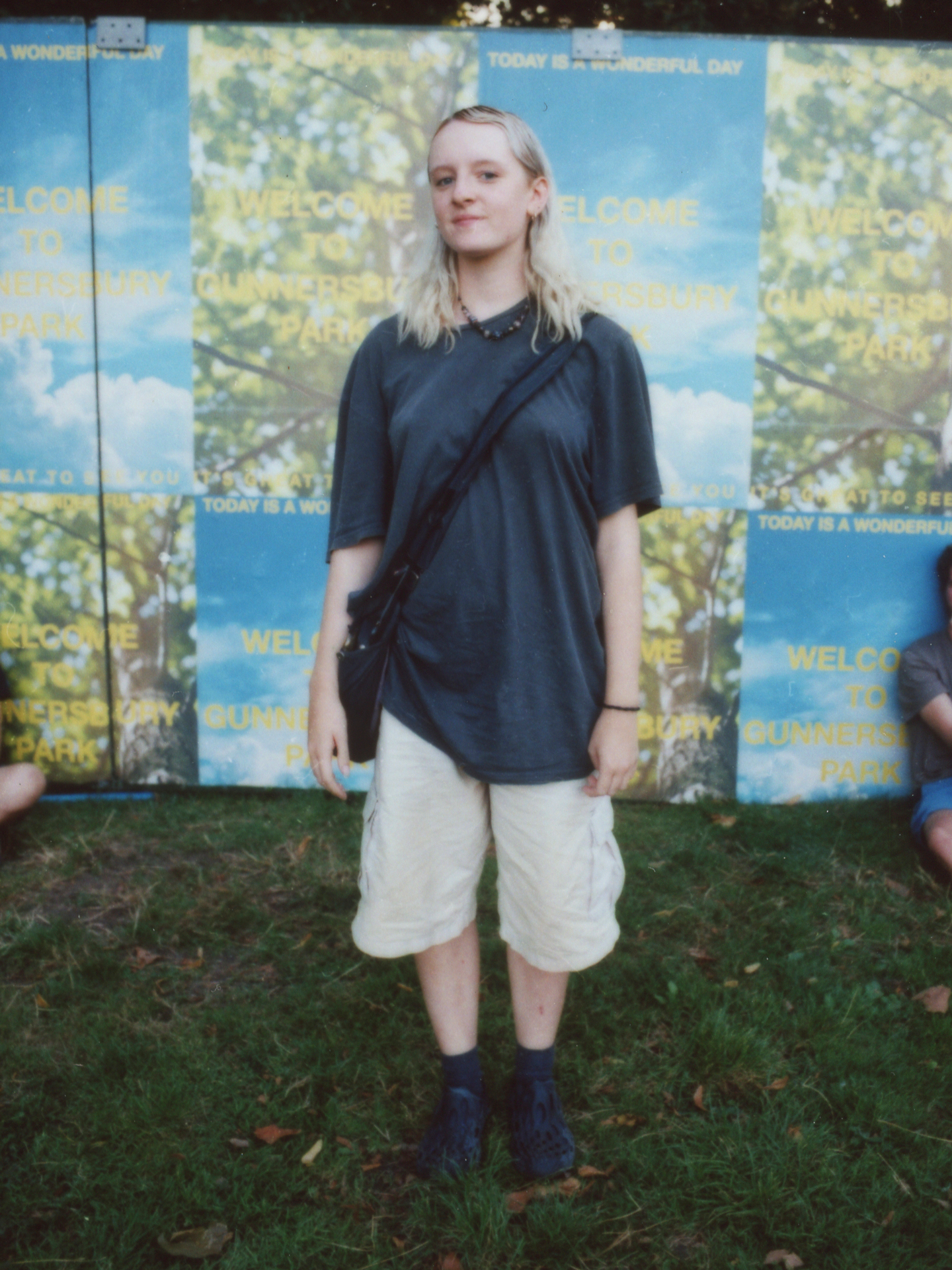 a festival-goer withmid-length bleach blonde hair wears an oversized tshirt and cargo shorts with merrell hydro mocs photographed by Jody Evans