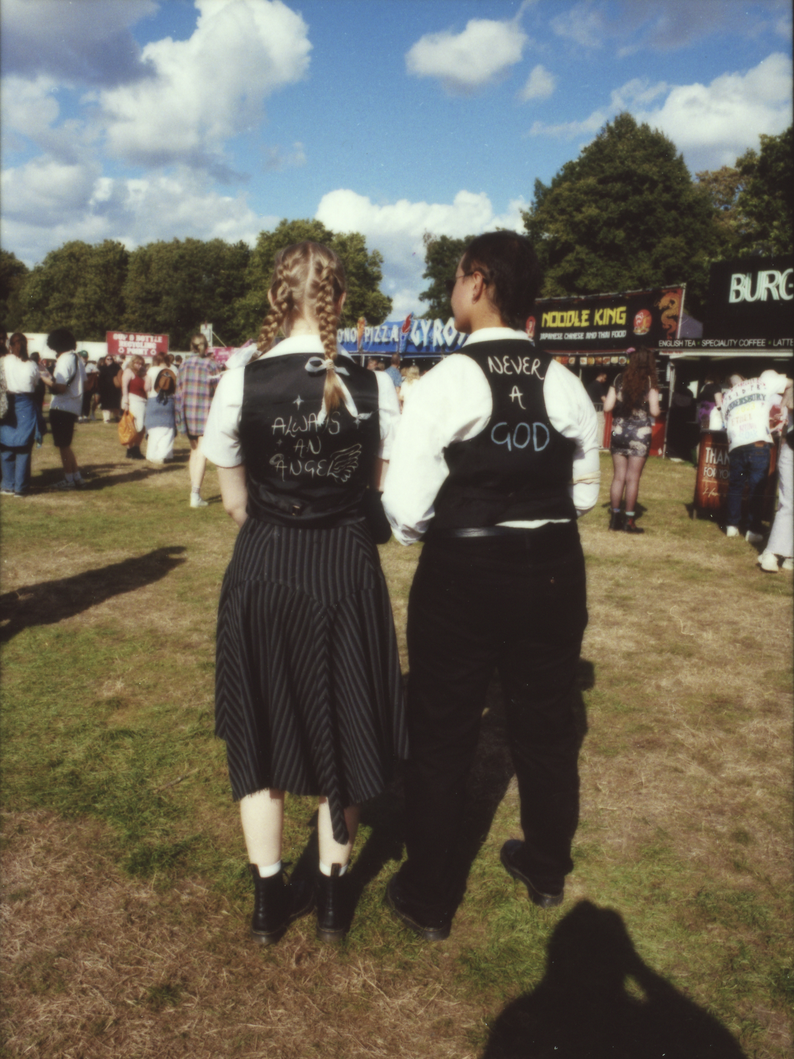 the backs of two people wearing matching vests over shirts; they have handwritten the lyrics 