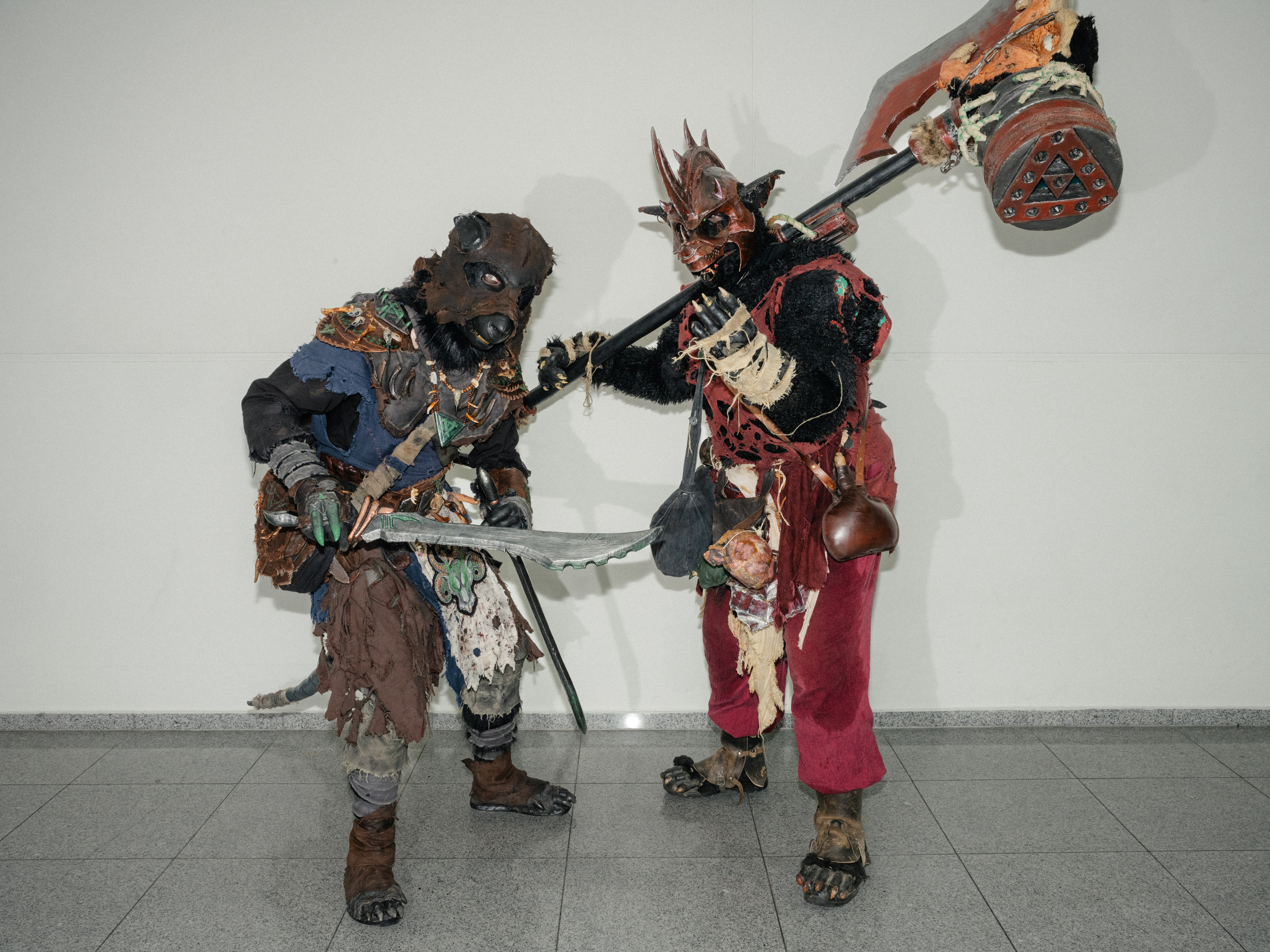 Zwei Männer tragen ein blaues und ein rotes LARP-Outfit, das an Skaven aus dem Warhammer-Universum angelehnt ist