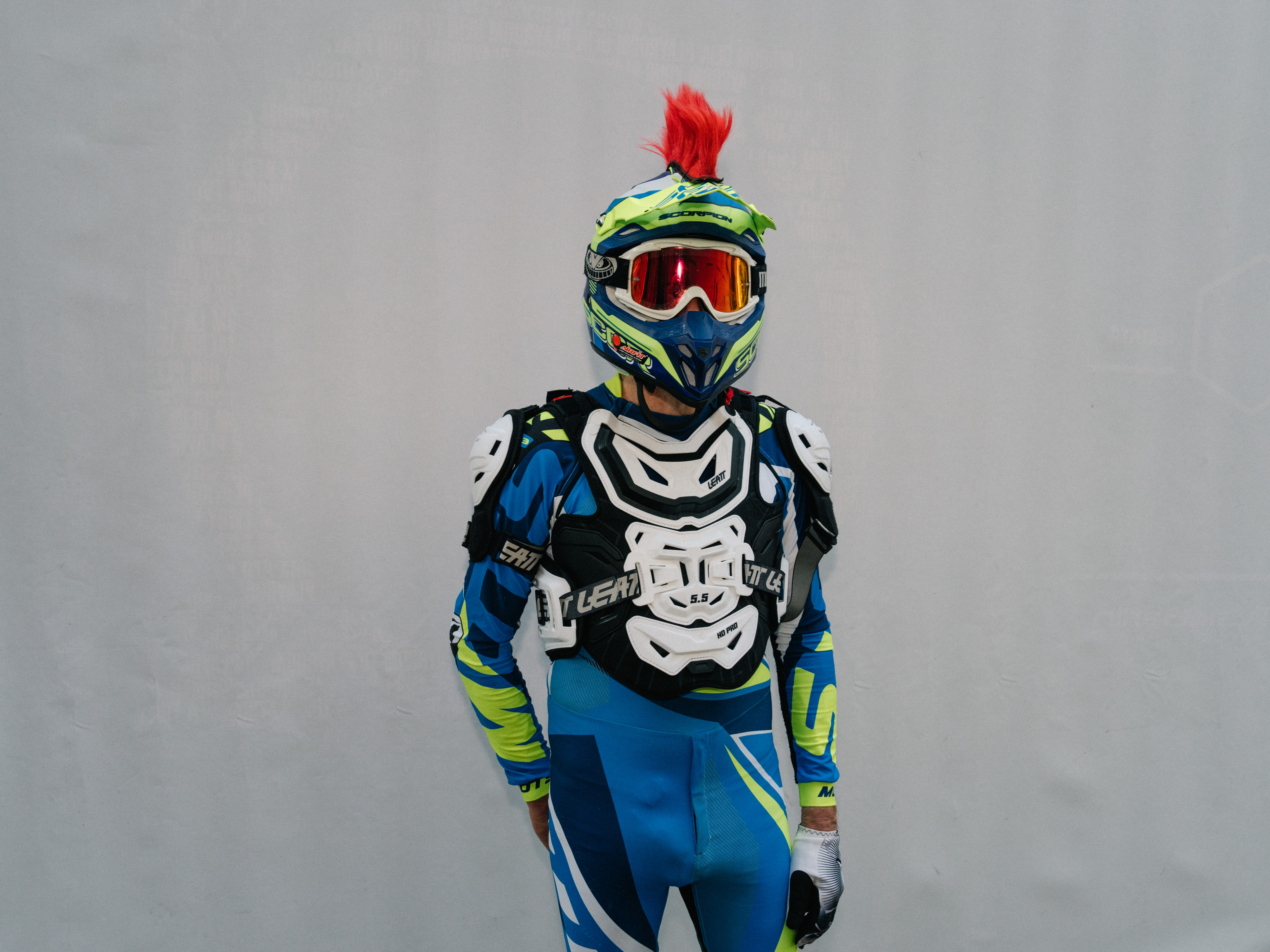Ein Mann trägt als Fetisch-Outfit ein buntes Motocross-Outfit mit Helm
