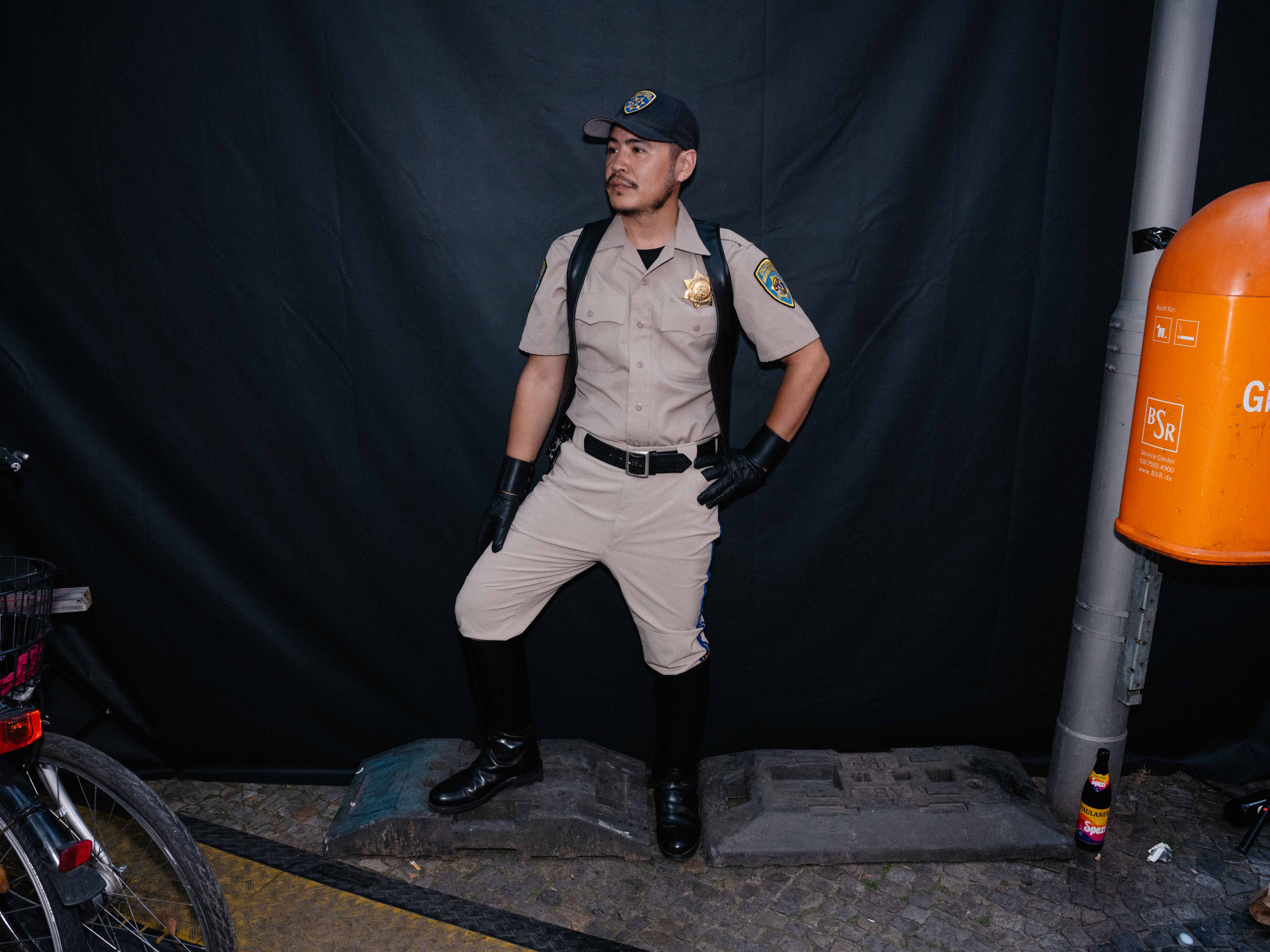 Ein Mann trägt ein US-Polizistenoutfit mit Lederstieferln bei einem Fetisch-Event