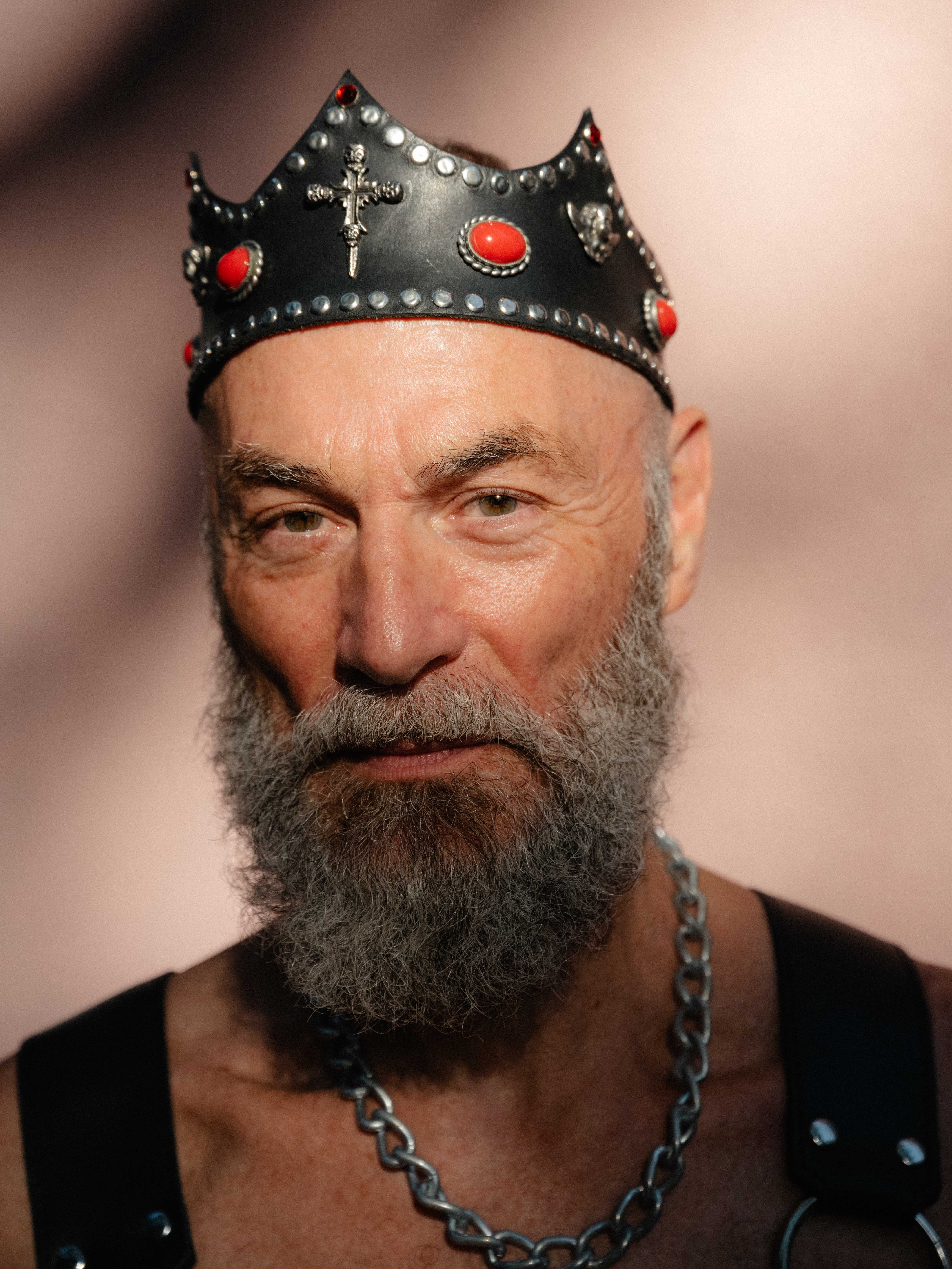 Ein Mann trägt einen grauen Bart und eine Krone aus Leder und Metallnieten