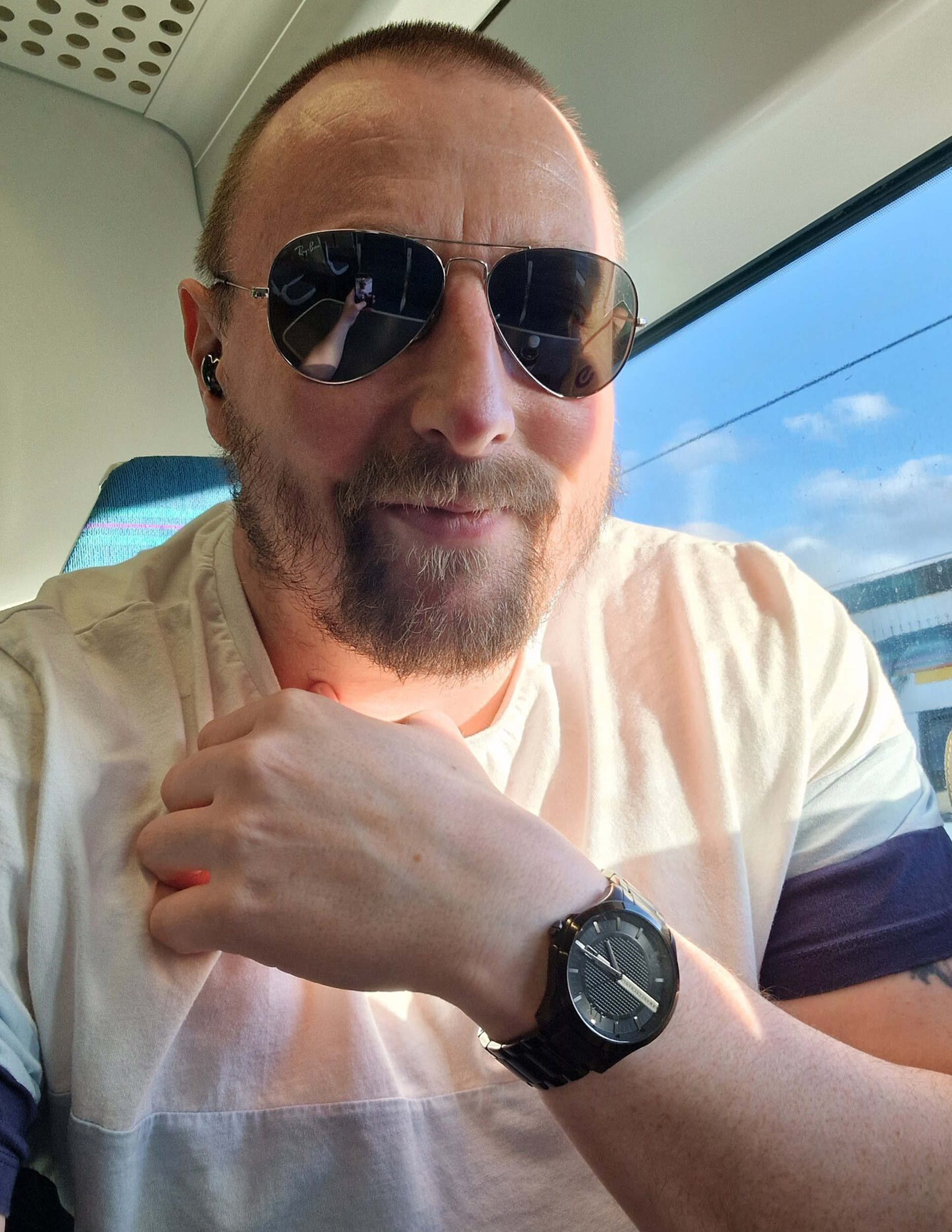 Selfie eines Mannes mit Fliegersonnenbrille und Bart in einem Zug