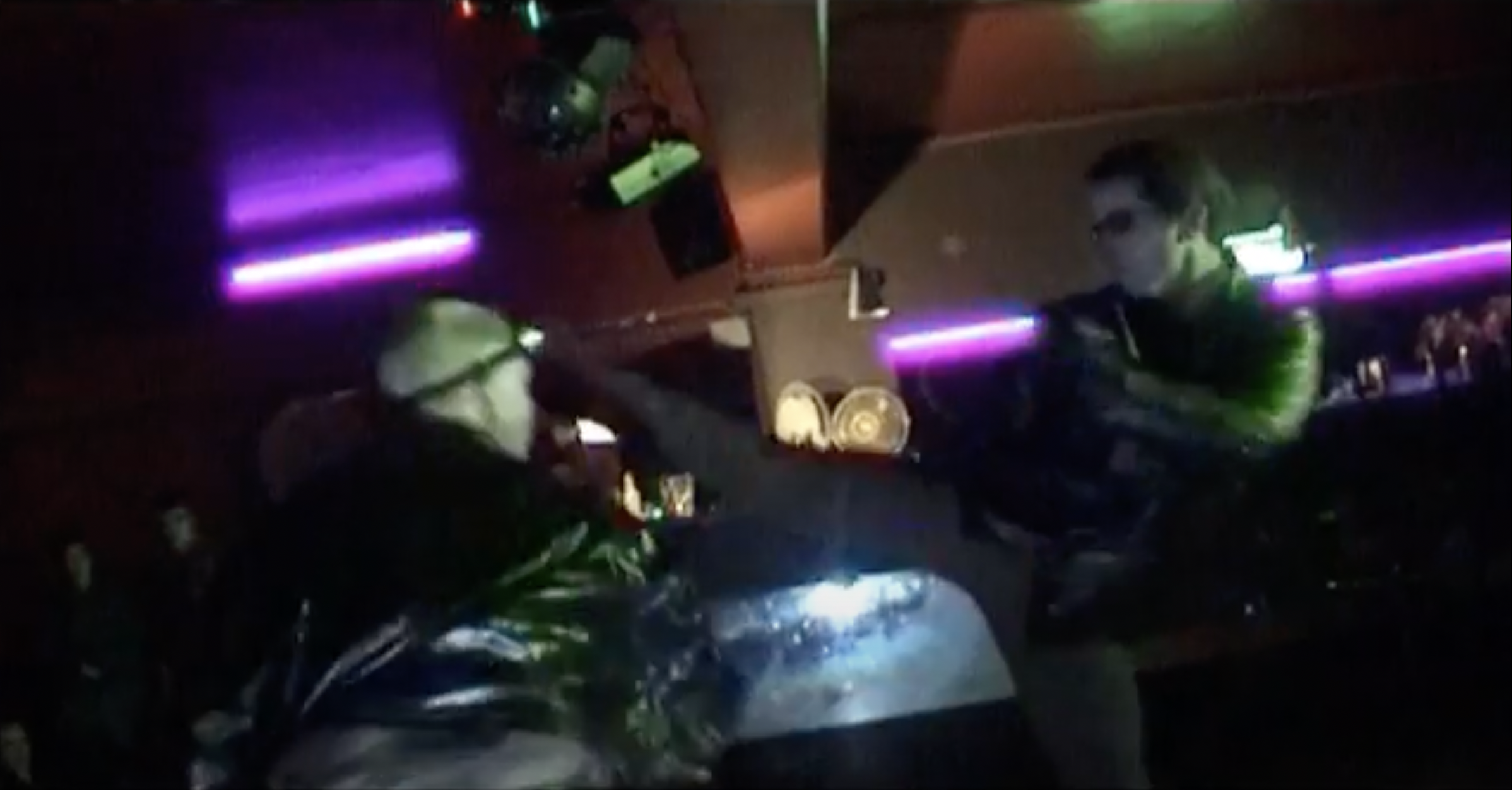 A screenshot from The Fanimatrix showing a man in sunglasses kicking someone in a nightclub with purple lights in the background.