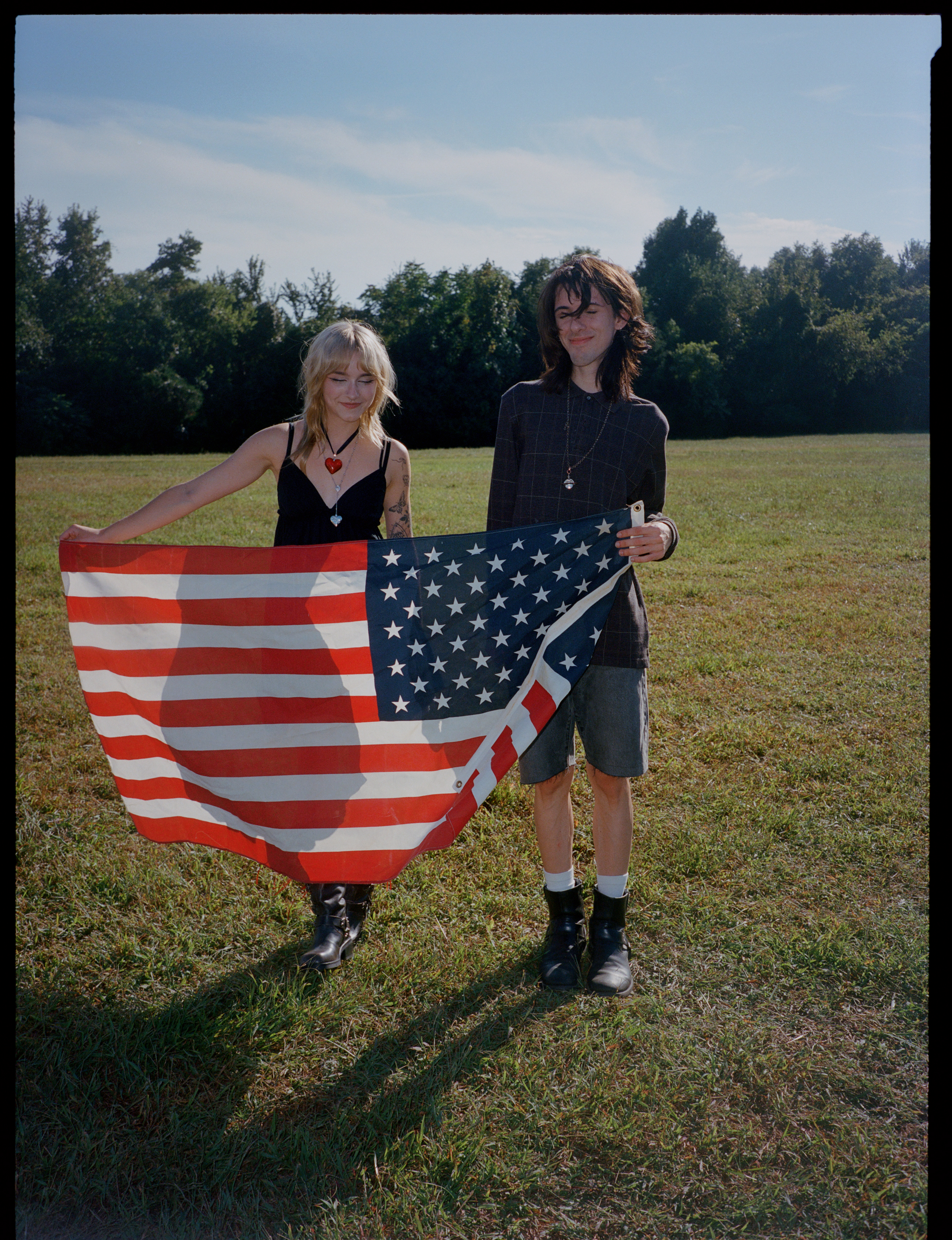 two lana del rey fans stand side-by-side, carrying a united states of america flag