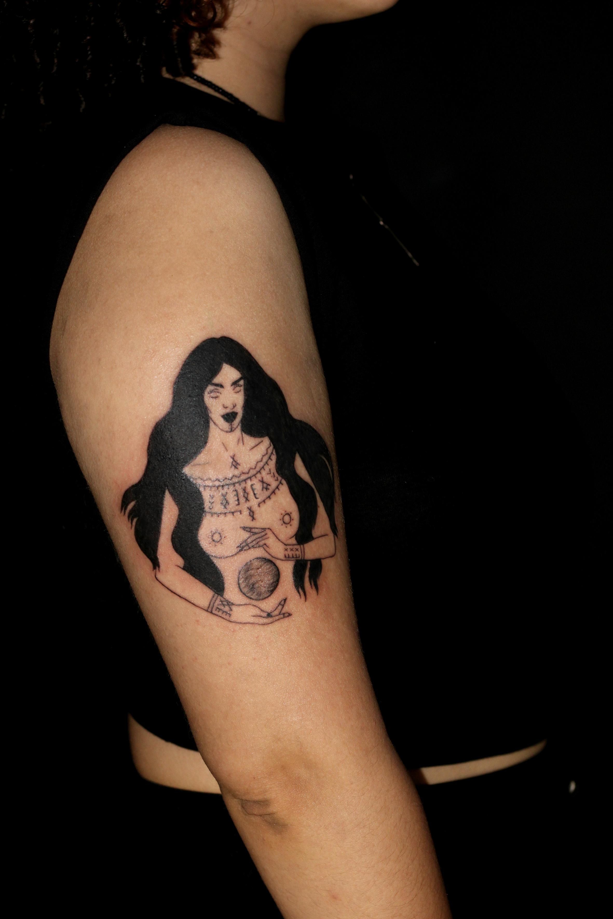 Side photo of tattoo on an arm featuring a women with long hair.