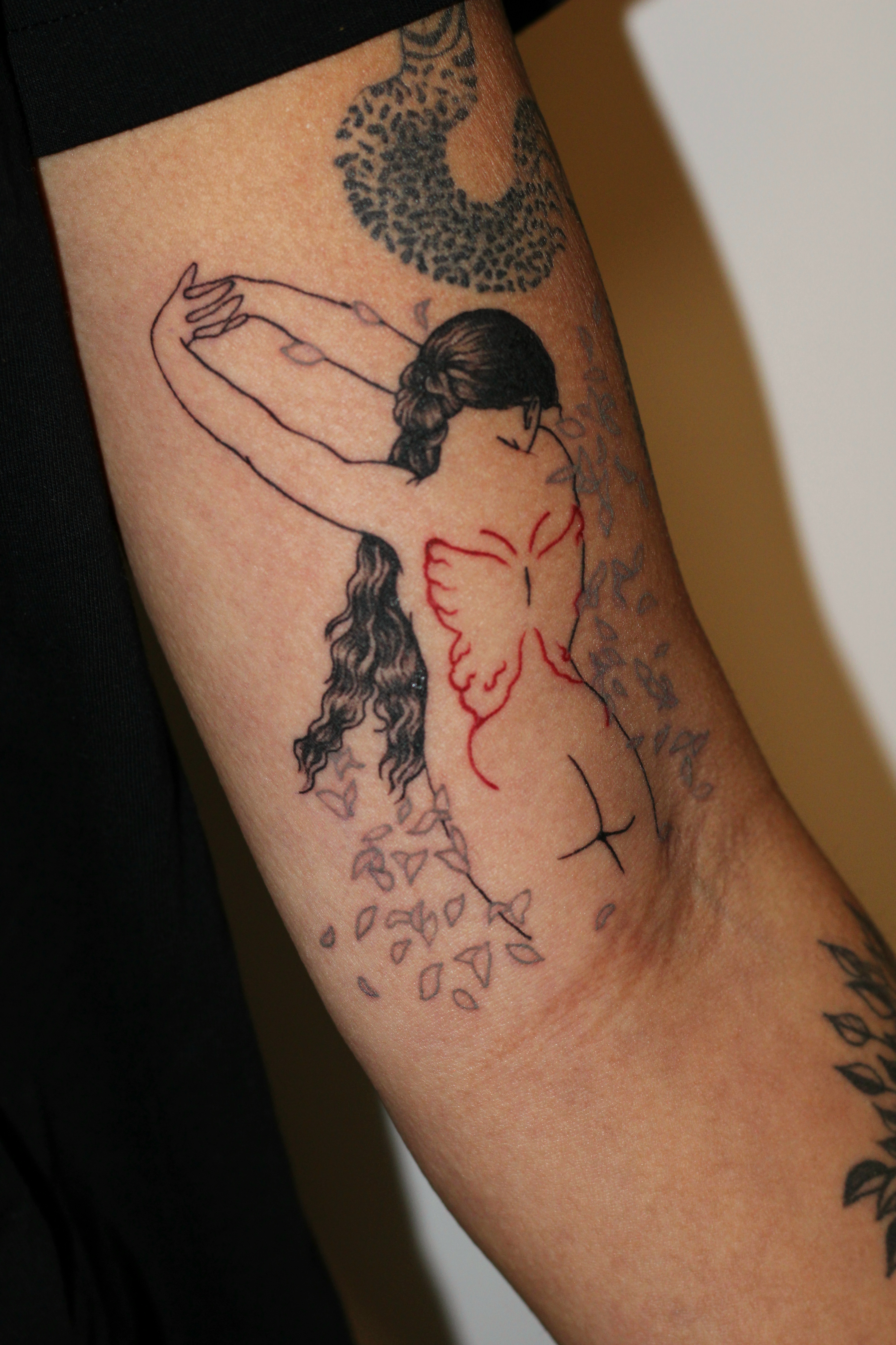 Photo of a tattooed upper arm featuring a naked woman from the back.
