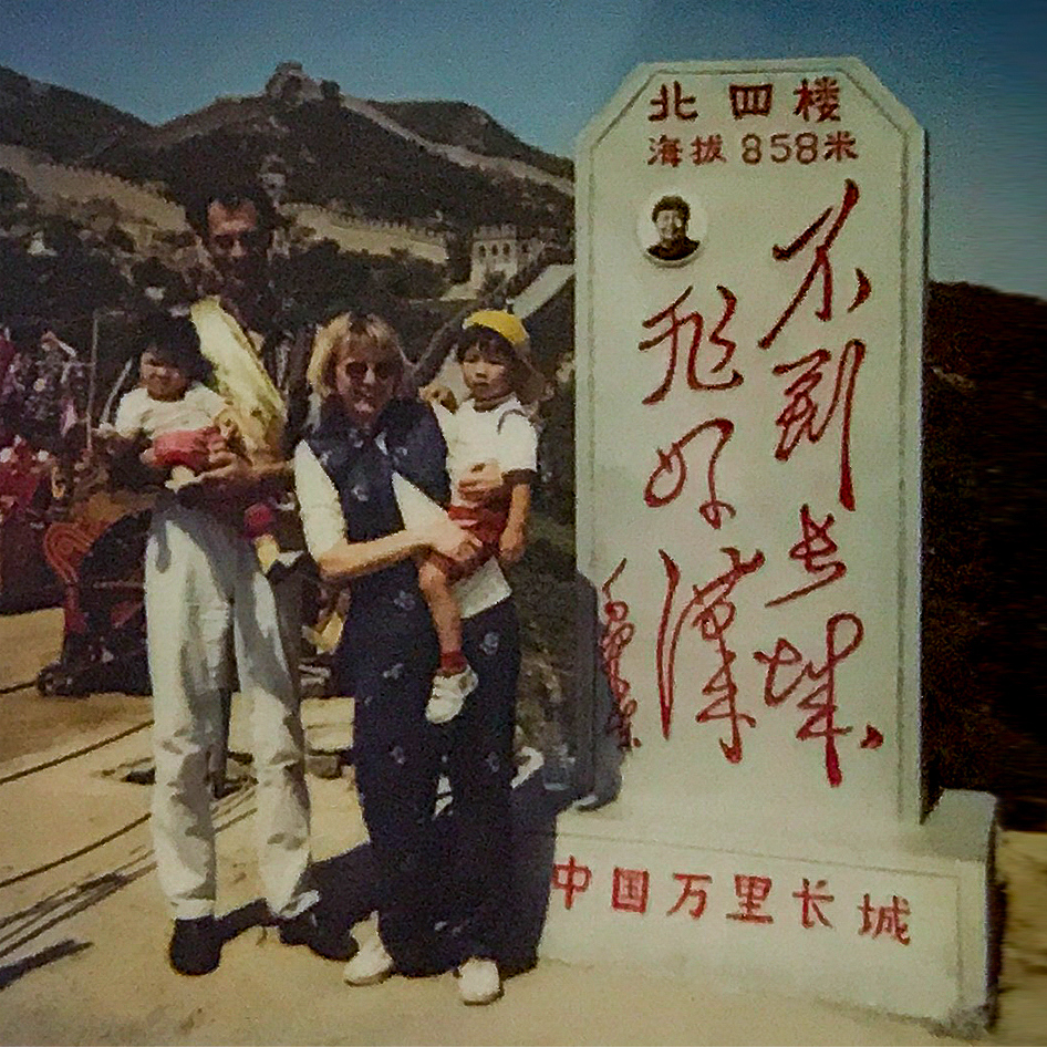 Xiangxia van den Ham, Dumpling Stories – vintage photo of a white couple holding two small Asian children in their arms and standing in front of the great wall of china.