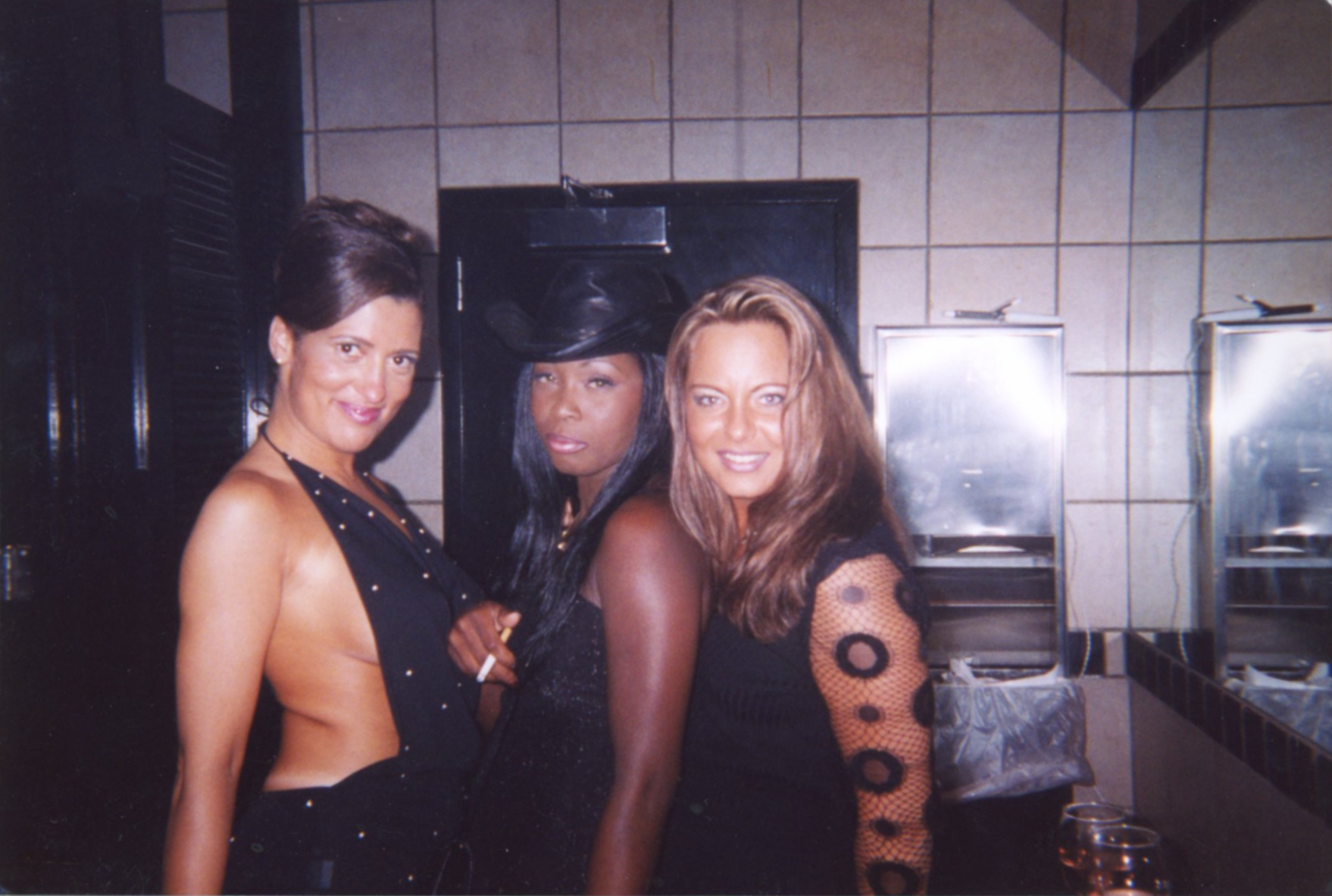 Drei Frauen posieren in einer Clubtoilette für ein Foto
