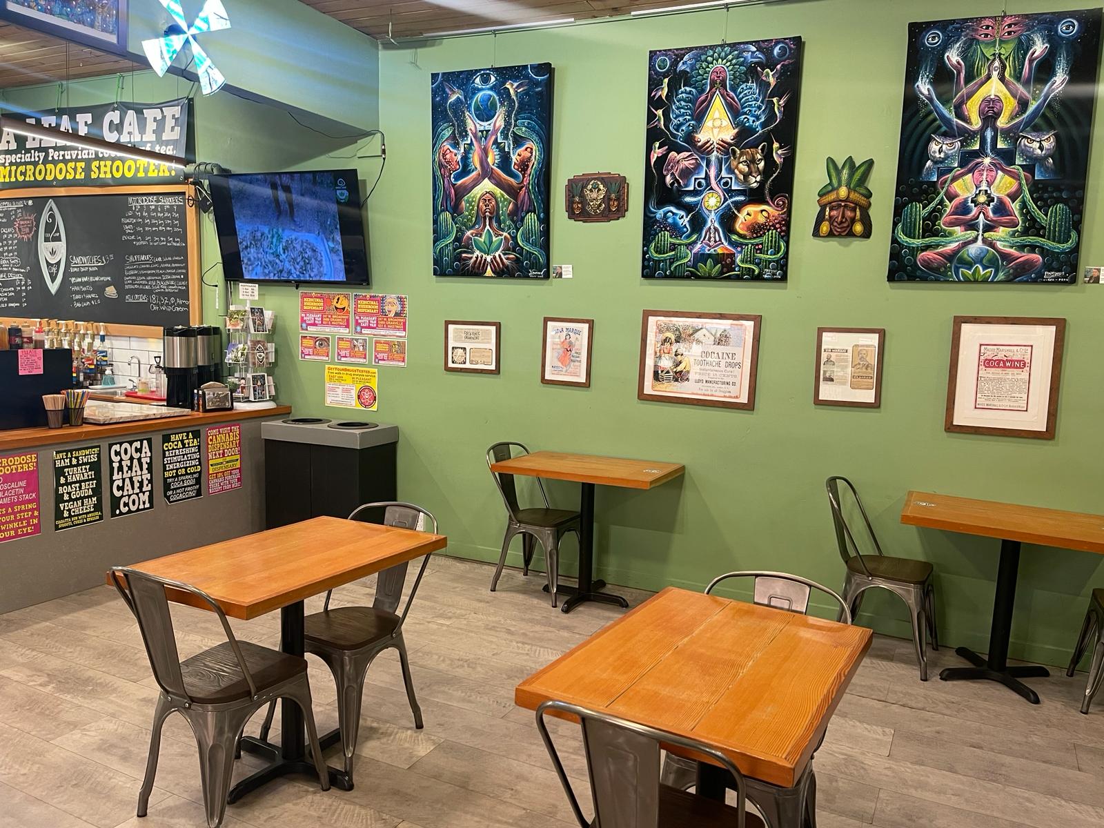 A photo of the inside of the cafe, showing tables and chairs and psychedelic art on the walls.