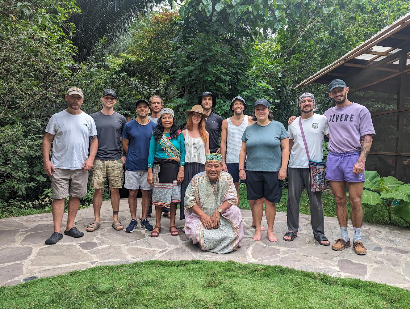 A group of 11 people on an ayahuasca retreat pose for a photo on a cobbled path with trees in background
