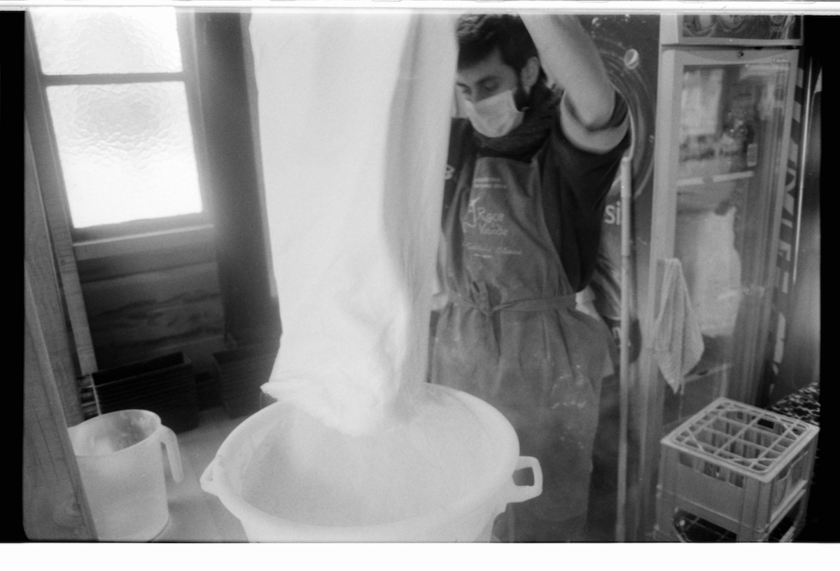 militant bakers - black and white blurry picture of a young man working on a big portion of bread dough in a room with a fridge in the background