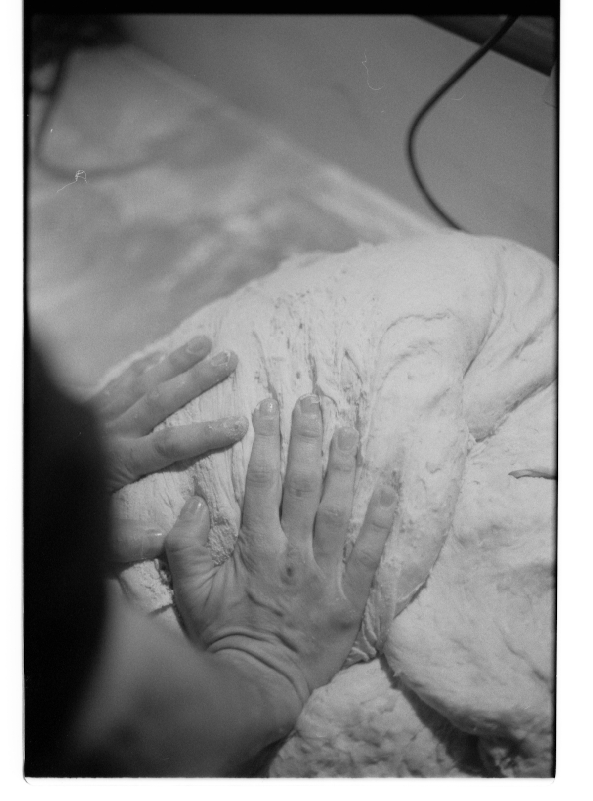 militant bakers - black and white blurry picture of two hands in bread dough
