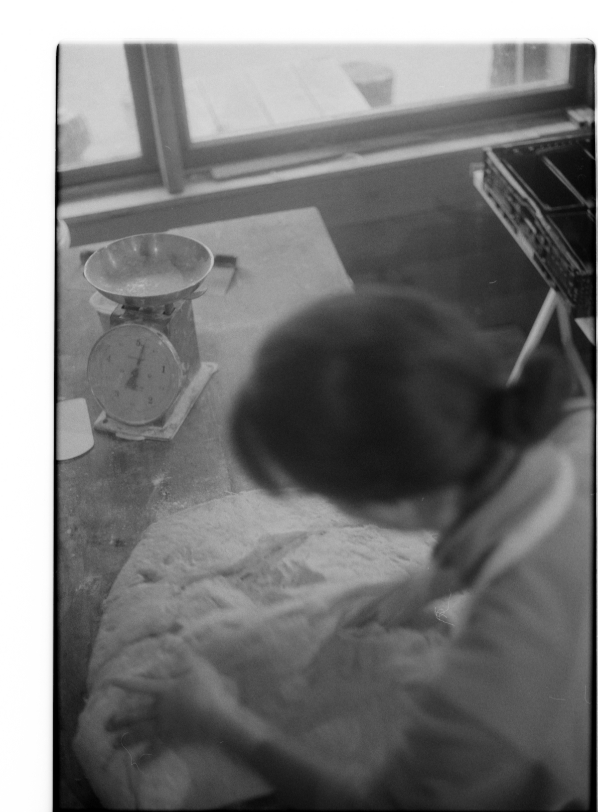 militant bakers - black and white blurry picture of a woman working on a big portion of bread dough