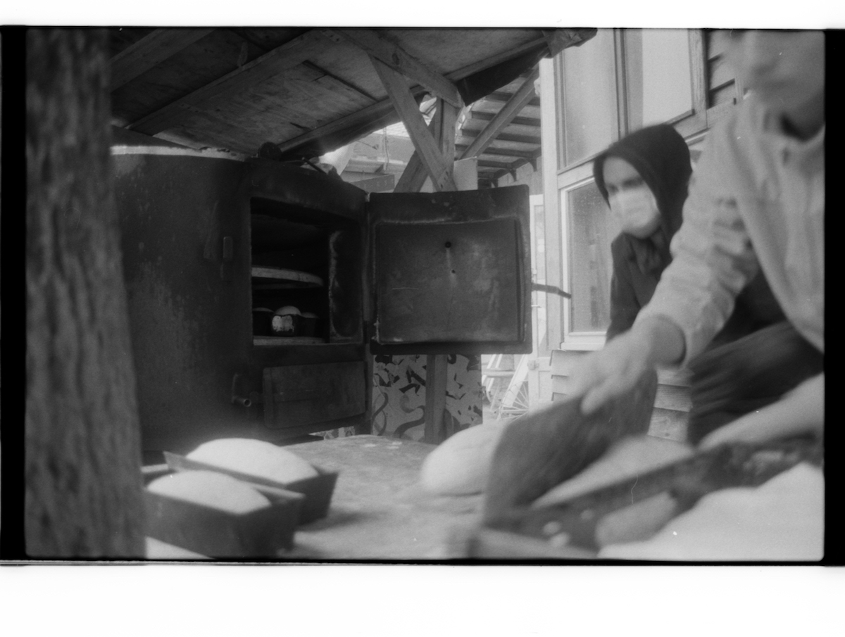 militant bakers - black and white blurry picture of two young men baking bread in a wood oven