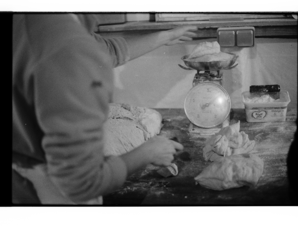militant bakers - black and white blurry picture of a person weighing portions of bread dough on an old scale
