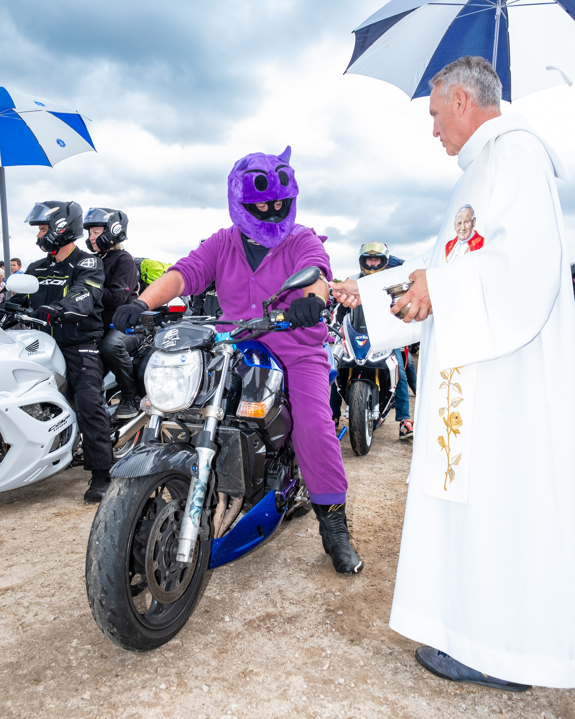 priest bless motorcycle rider at Le Pardon des Motards pilgrimage in porcaro brittany france