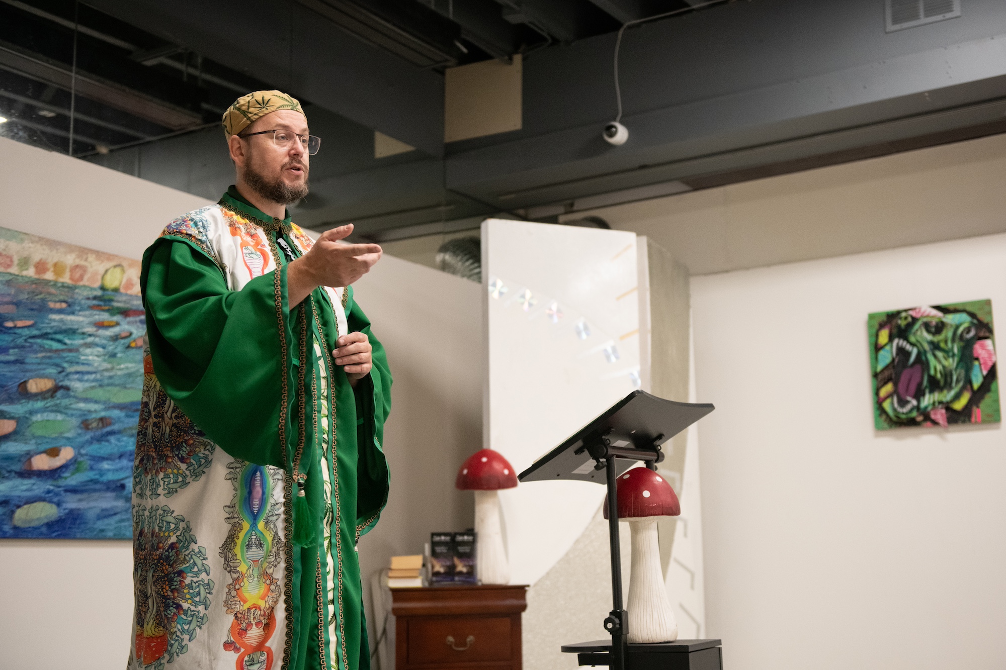 A man in green robes preaches from a mushroom themed pulpit.