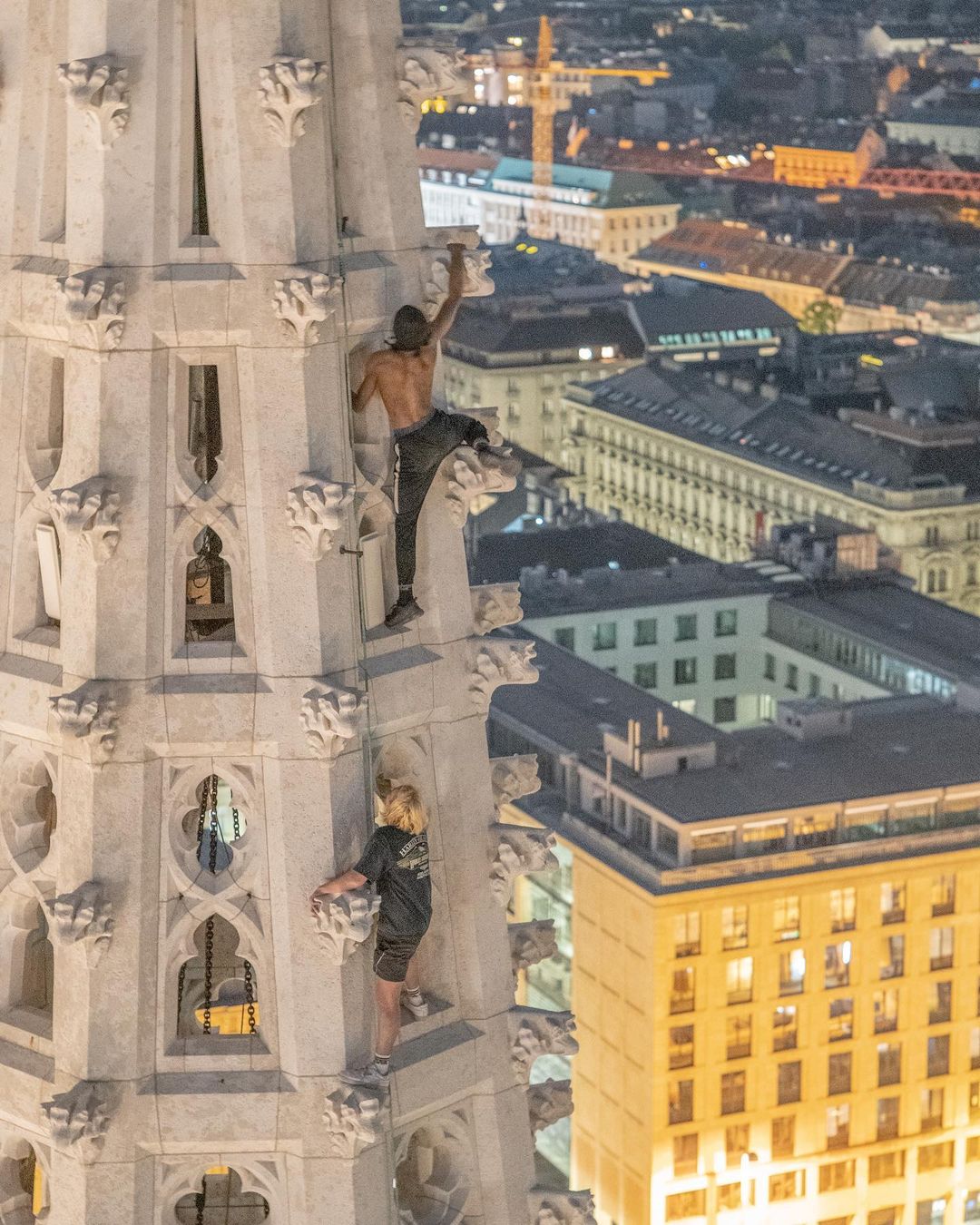 Two men climb up a church in Europe.