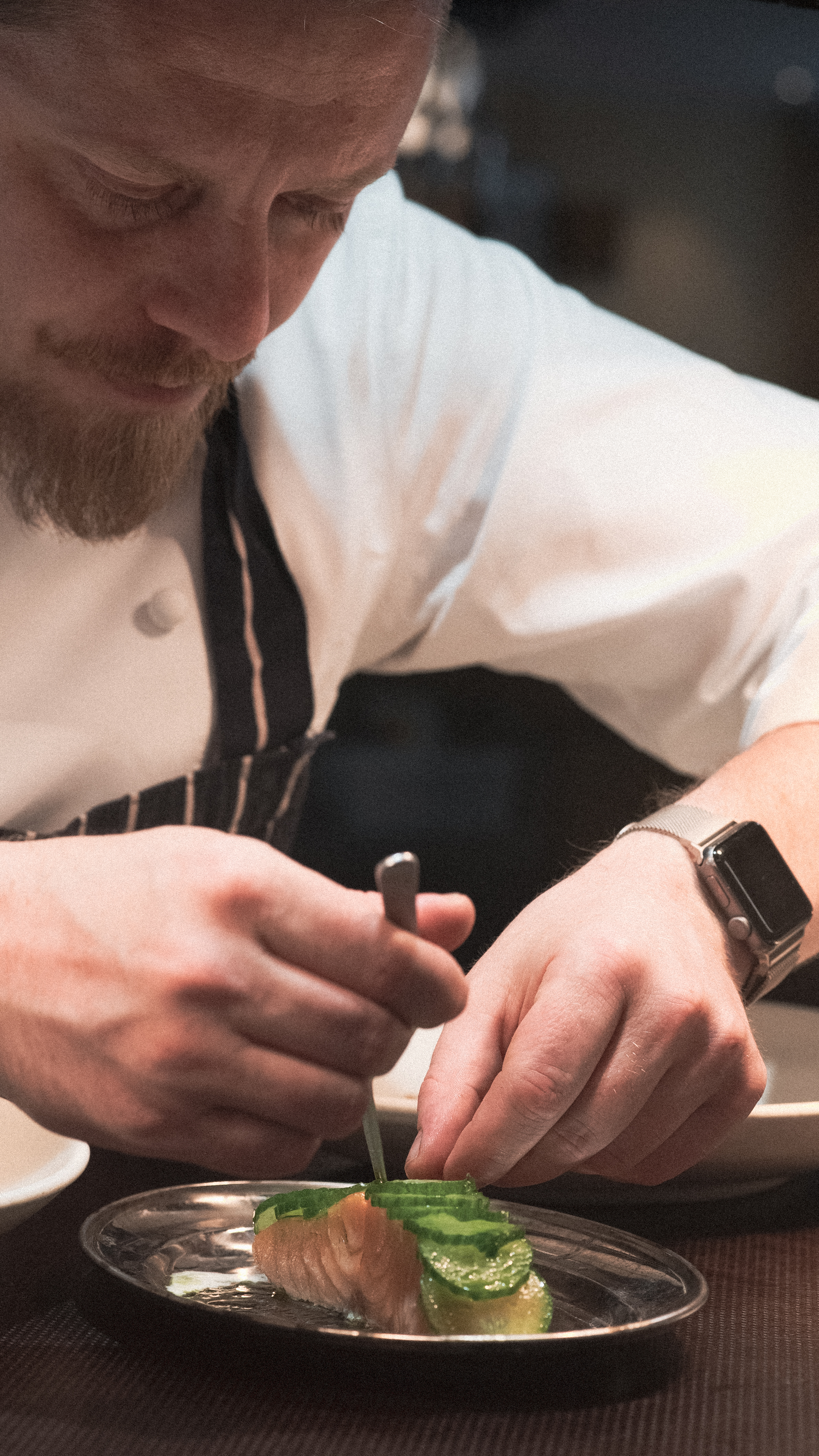 Chef working on a salmon dish in a restaurant kitchen.