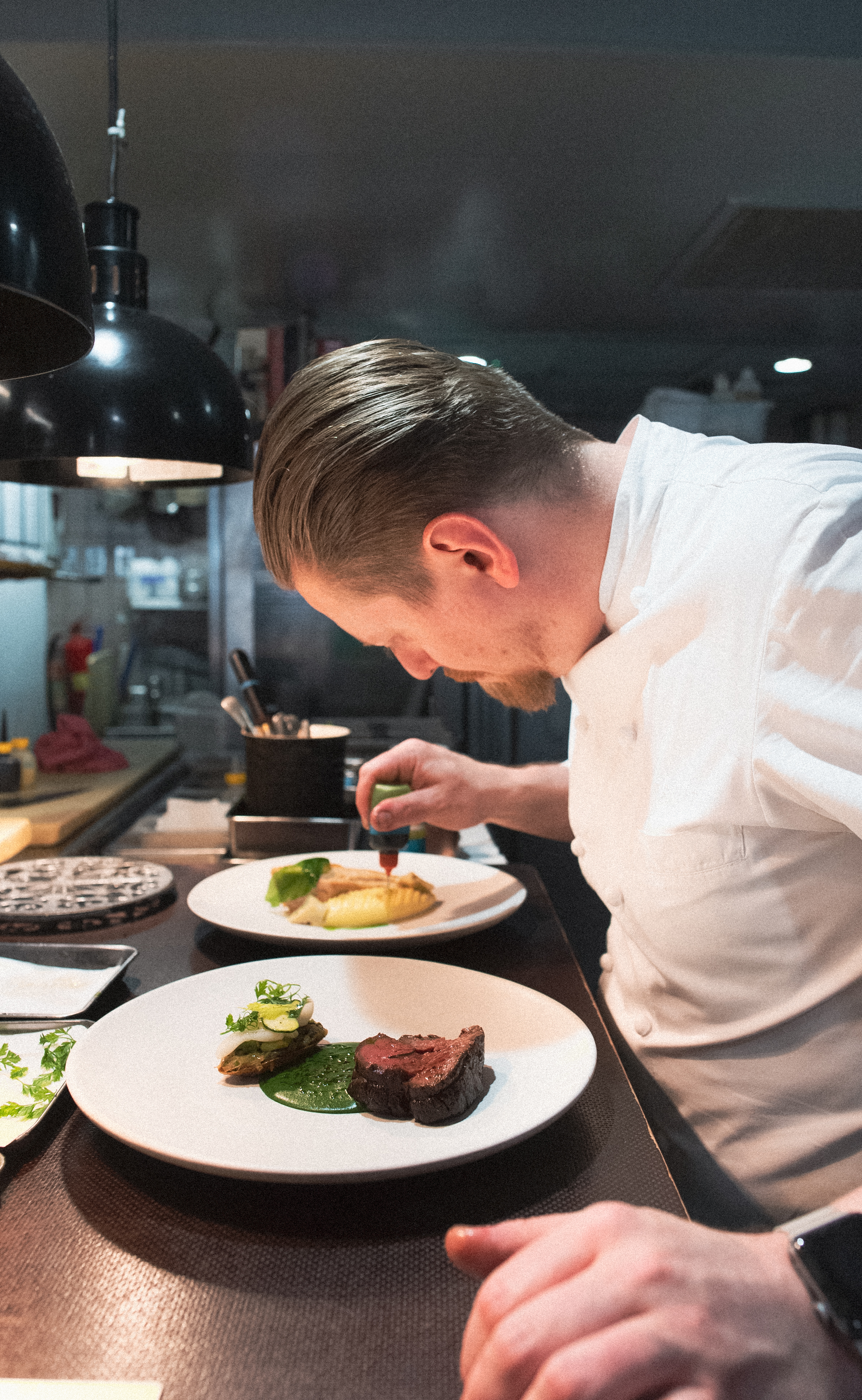 Chef applying finishing touches to restaurant dishes.