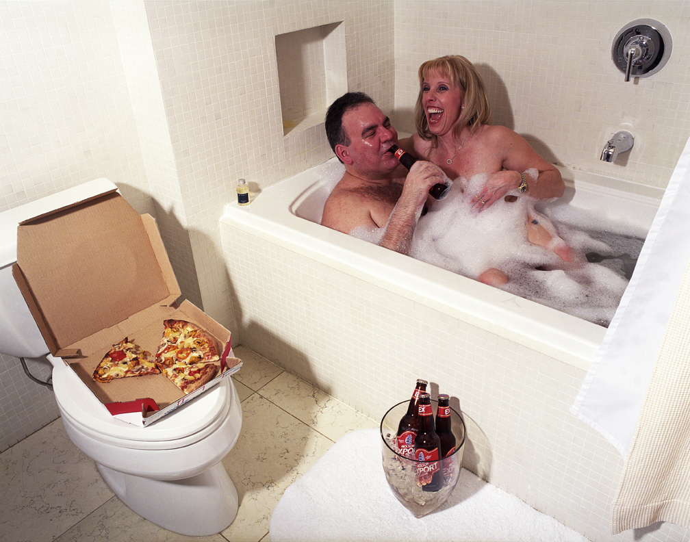 swingers drinking beer and eating pizza in a hotel bathtub