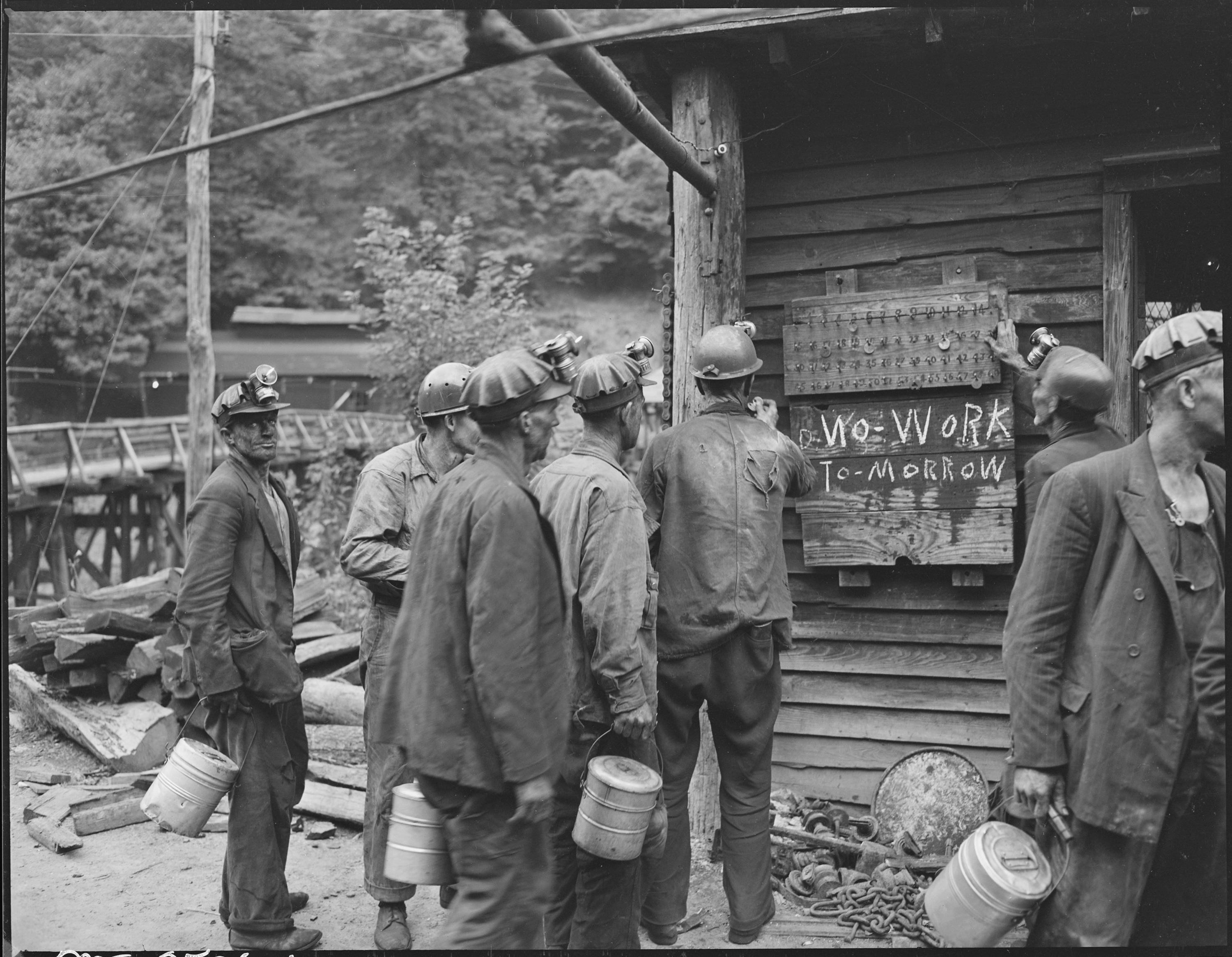 1581526204251-Miners_bring_in_their_checks_and_see_the_sign_that_there_is_no_Saturday_work_P_V_and_K_Coal_Company_Clover_Gap_Mine_-_NARA_-_541295