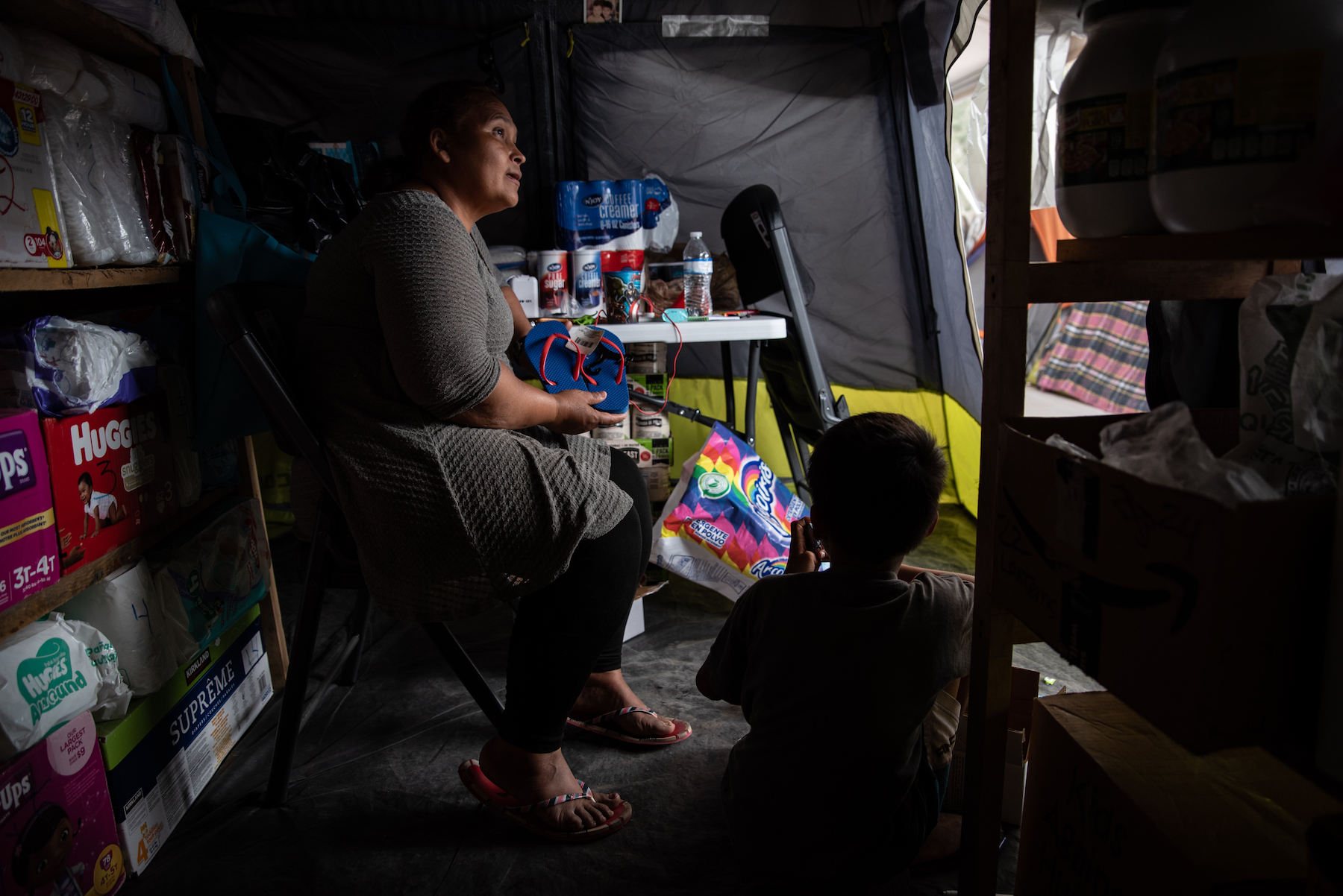 Roxana de Castro sits inside a supply tent while listening to a request from a fellow migrant. Photo: Sergio Flores/VICE News.