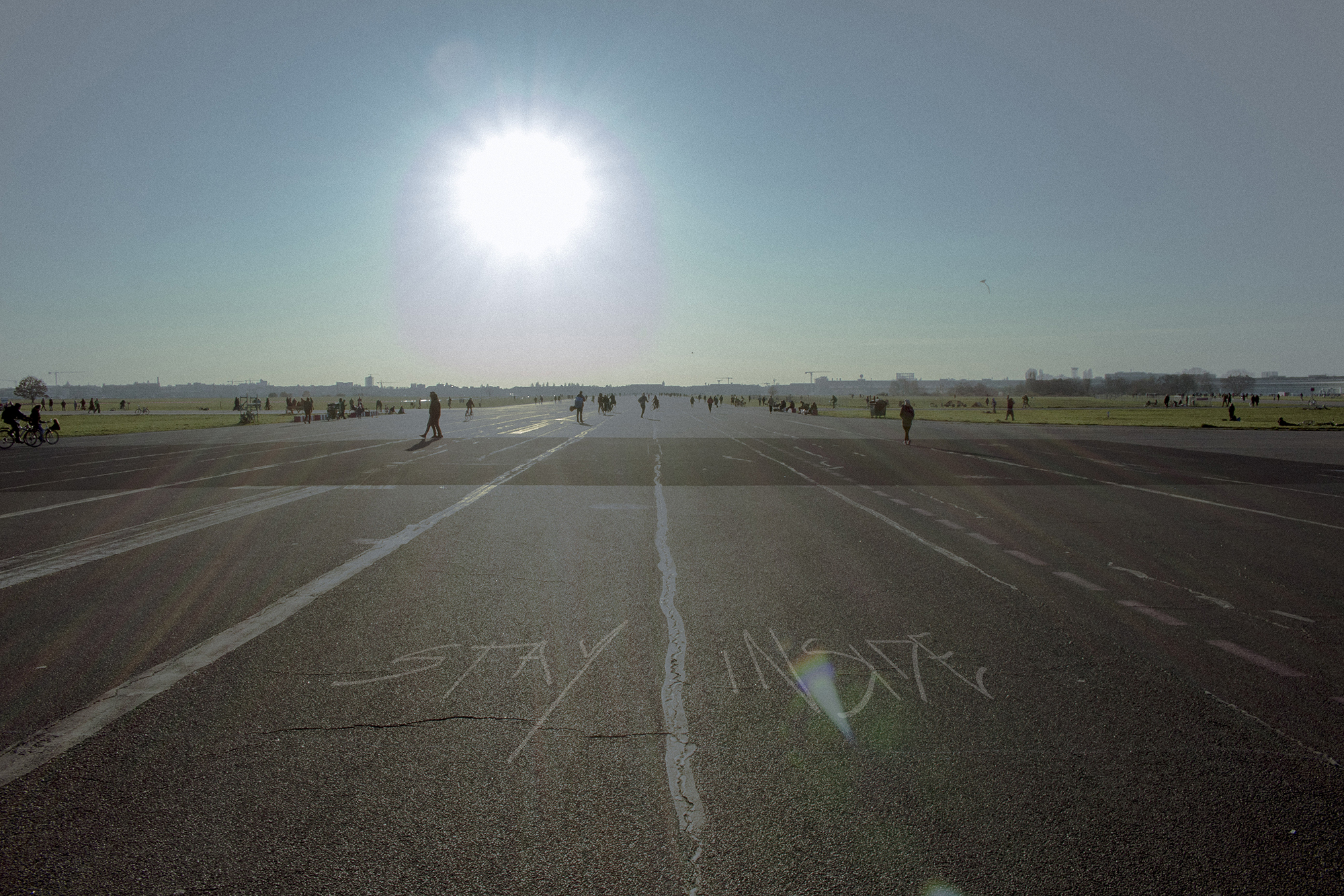 Das Tempelhofer-Feld mit einigen Spaziergängern. Auf dem Asphalt steht