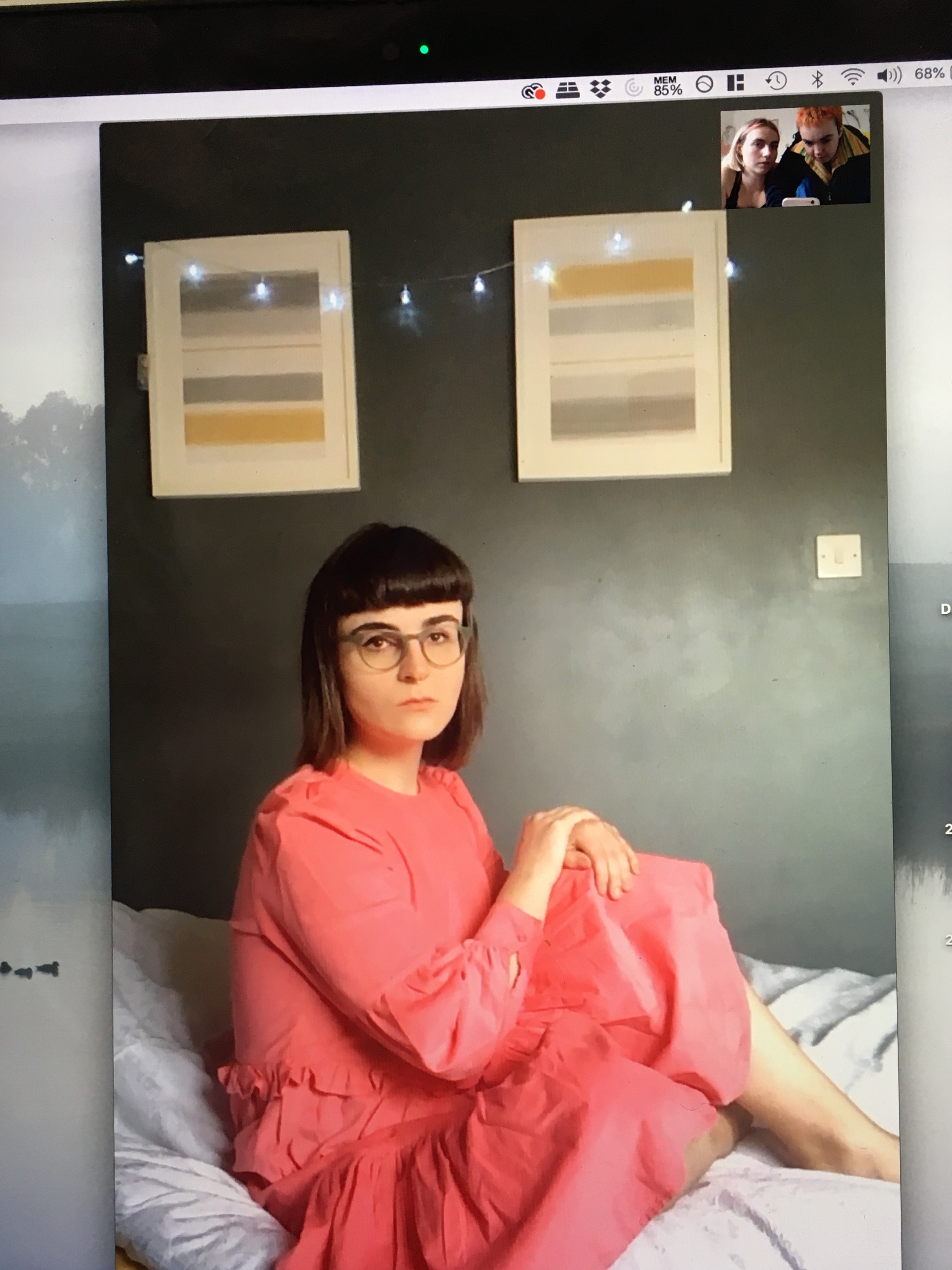 A person wearing a pink dress sitting on their bed, part of Glazzard's photo series of social distance, among the uplifting LGBT+ news headlines during COVID-19