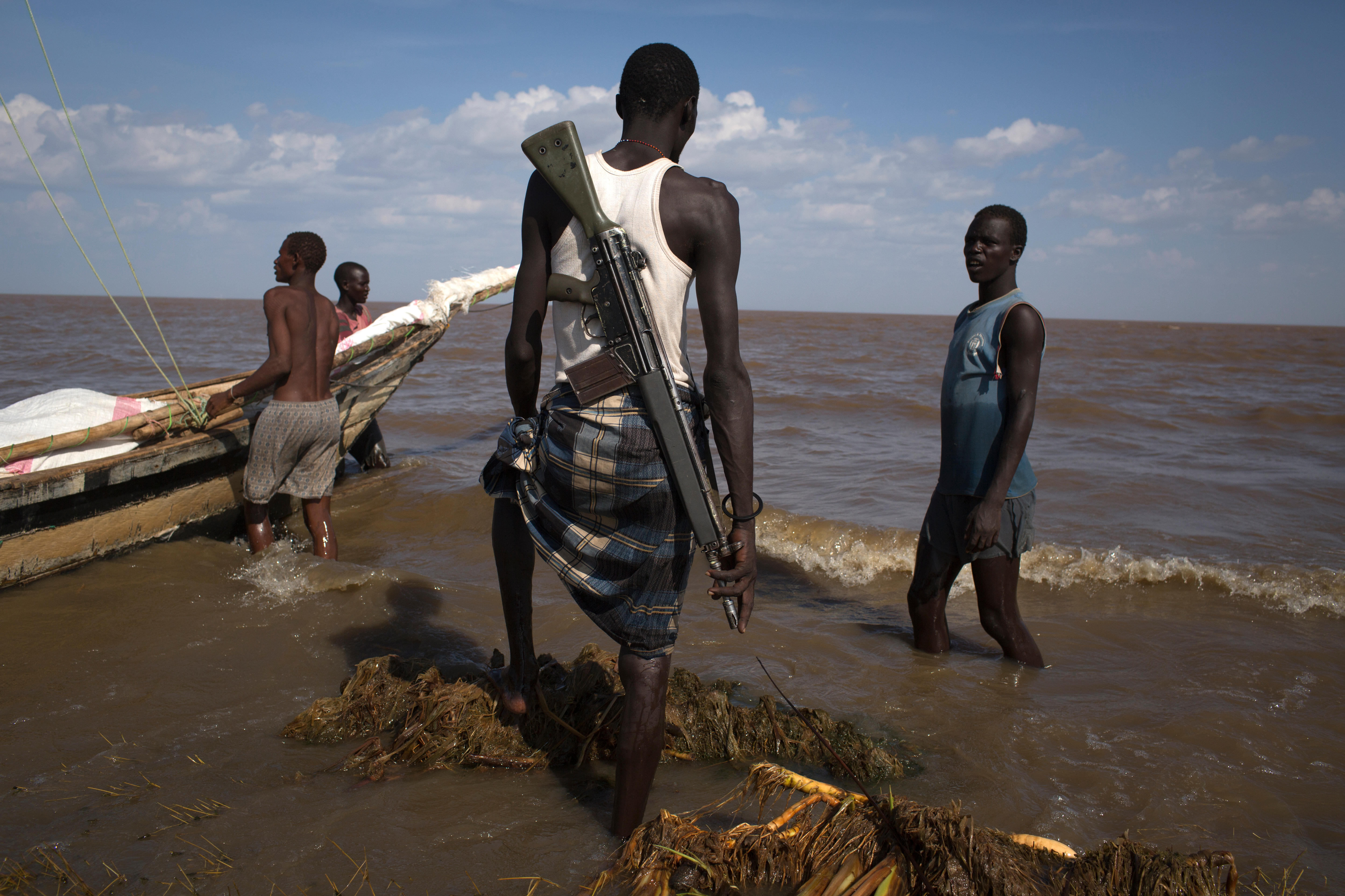 Armed Kenyan fishermen prepare to sail their boat on Lake Turkana. Photo: Siegfried Modola / Alamy