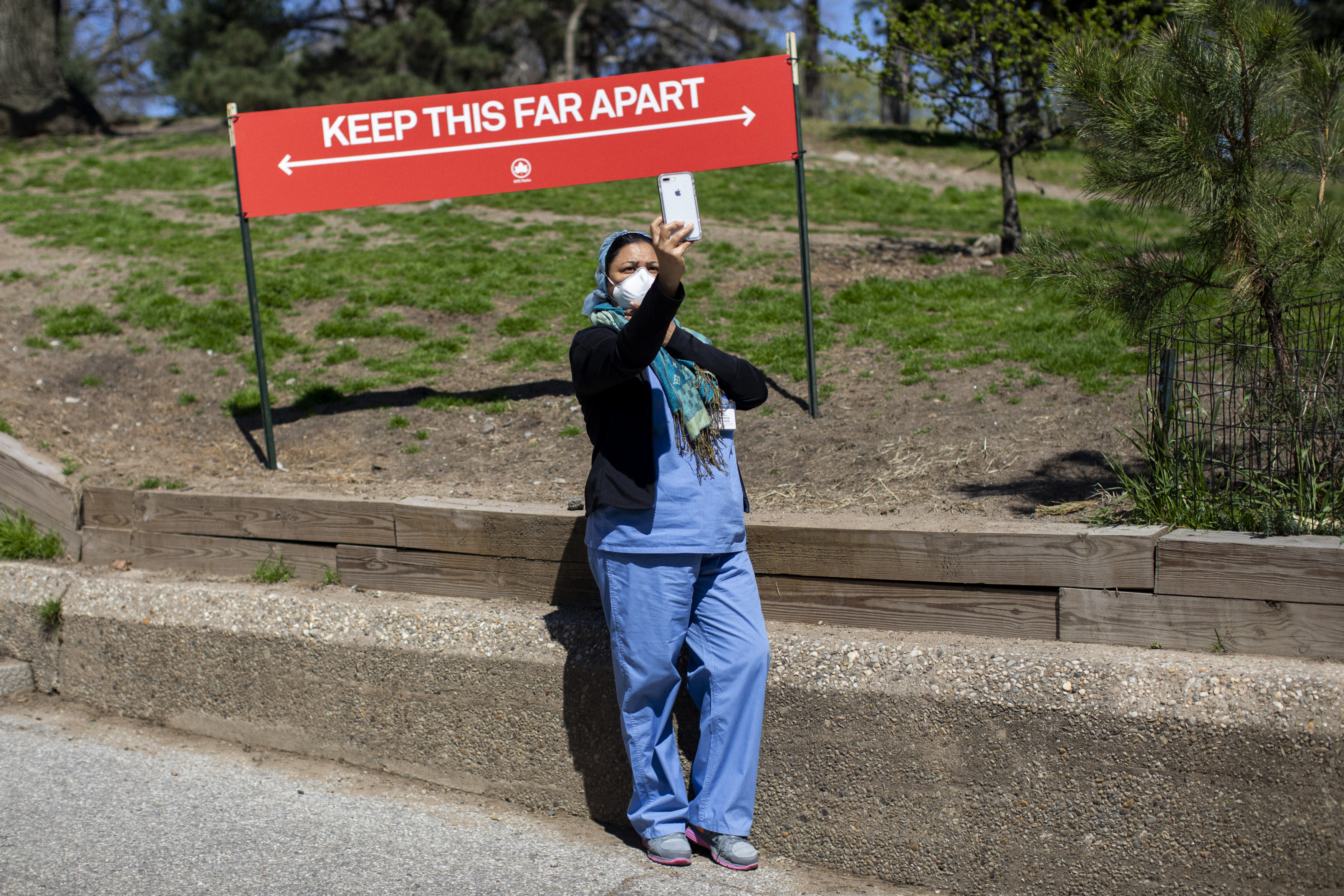 In Brooklyn a healthcare worker takes a selfie in front of a social distancing sign in Ft. Greene Park. April 06, 2020