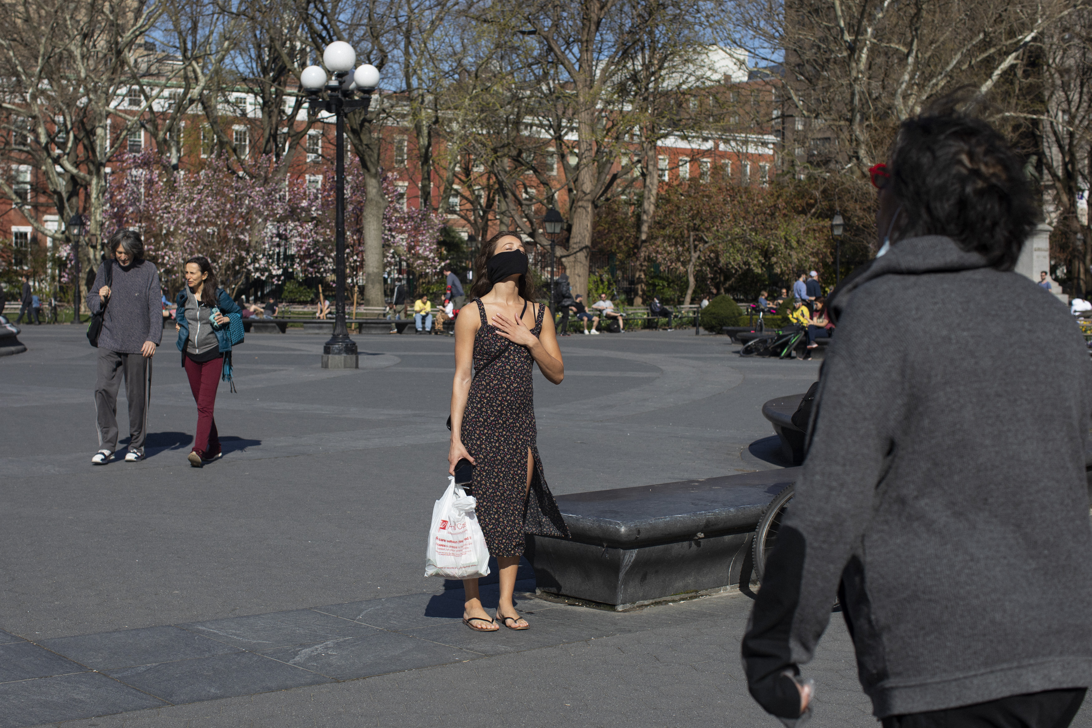 A woman pauses in the warm sun while walking through Washington Square Park. April 06, 2020