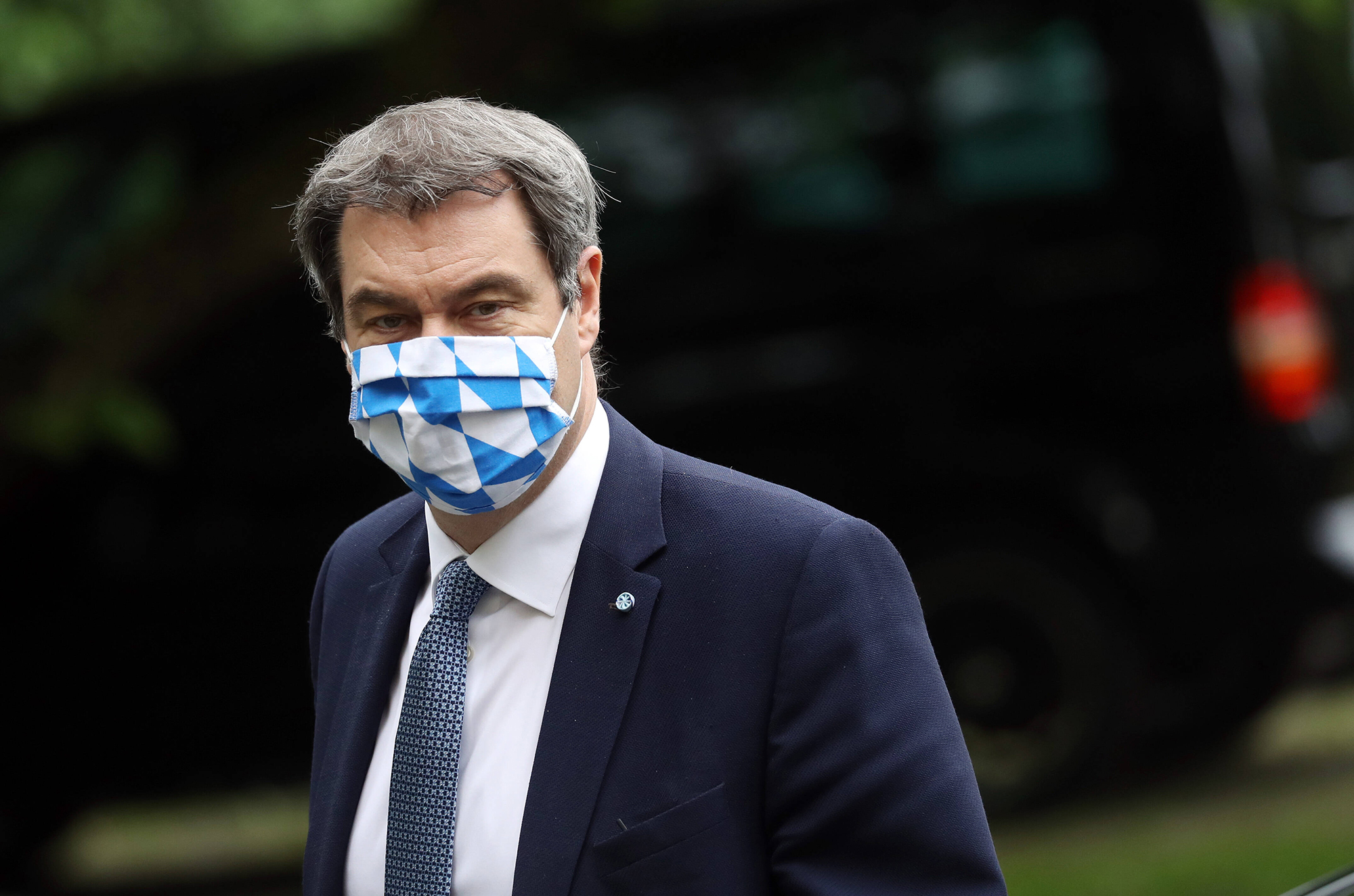 Markus Söder trägt eine Maske mit dem Muster der bayrischen Flagge