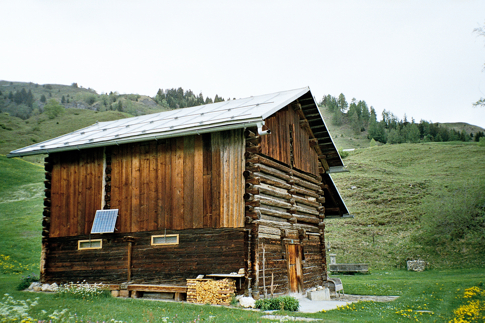 Die Holzhütte von aus außen in einem Berg-Panorama