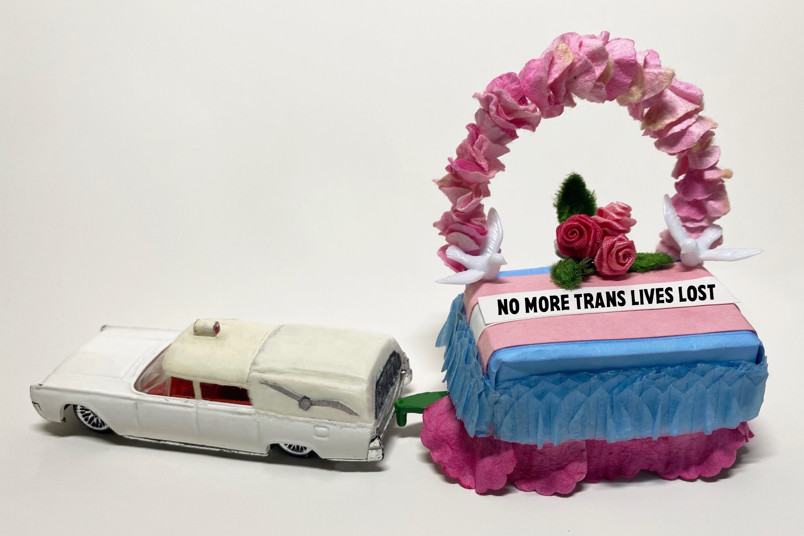 miniature white hearse pulling a blue and pink 