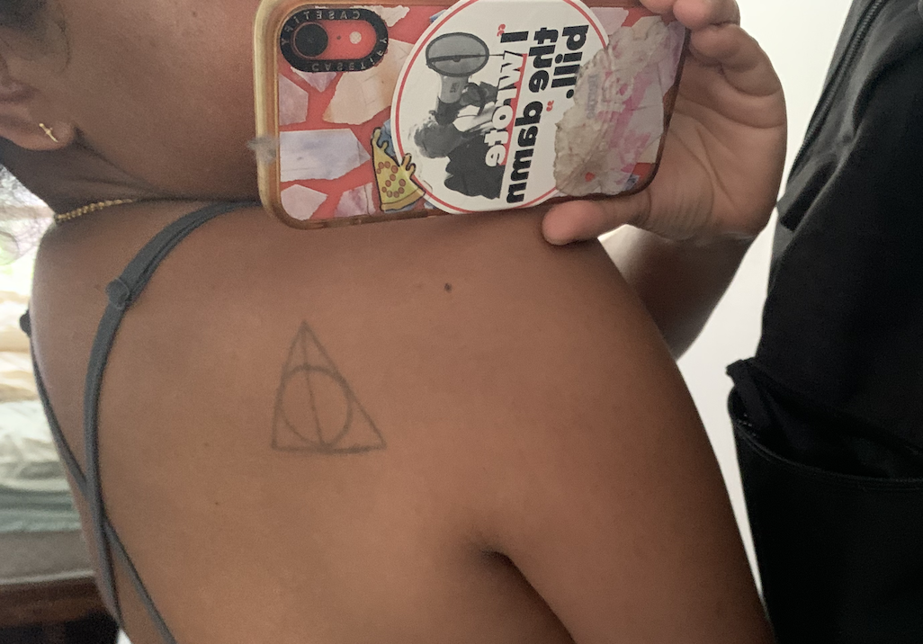 A deathly hallows tattoo on someone's back.