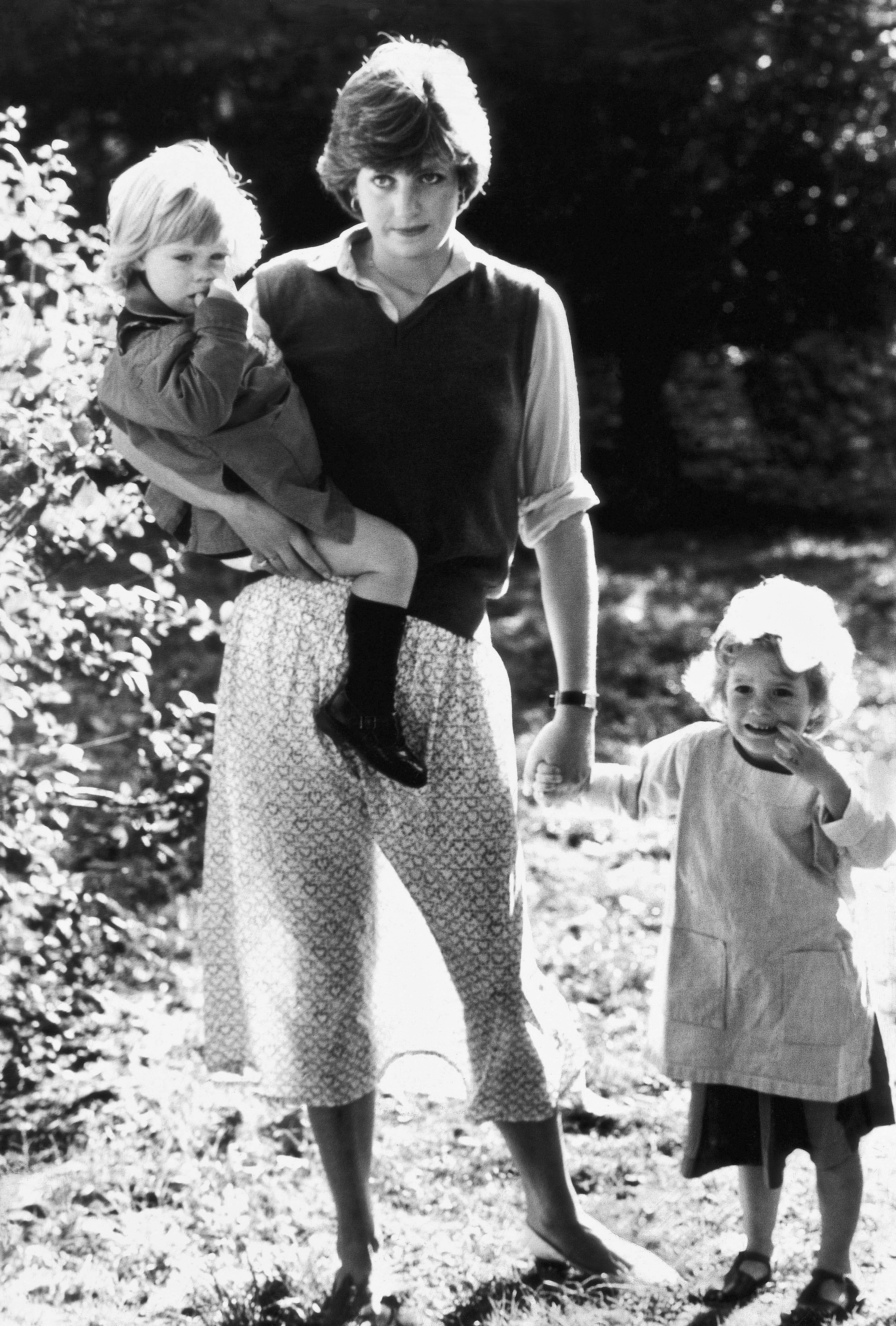 A black and white portrait of Diana wearing a long dress and a boat skirt with two children