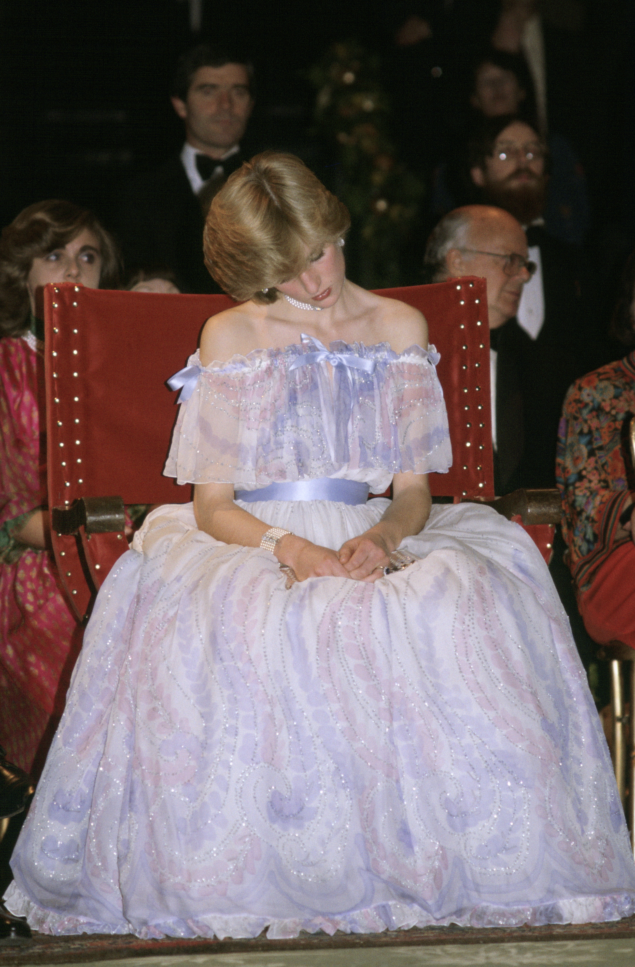 A photo of Princess Diana sitting and laughing in a purple ball gown