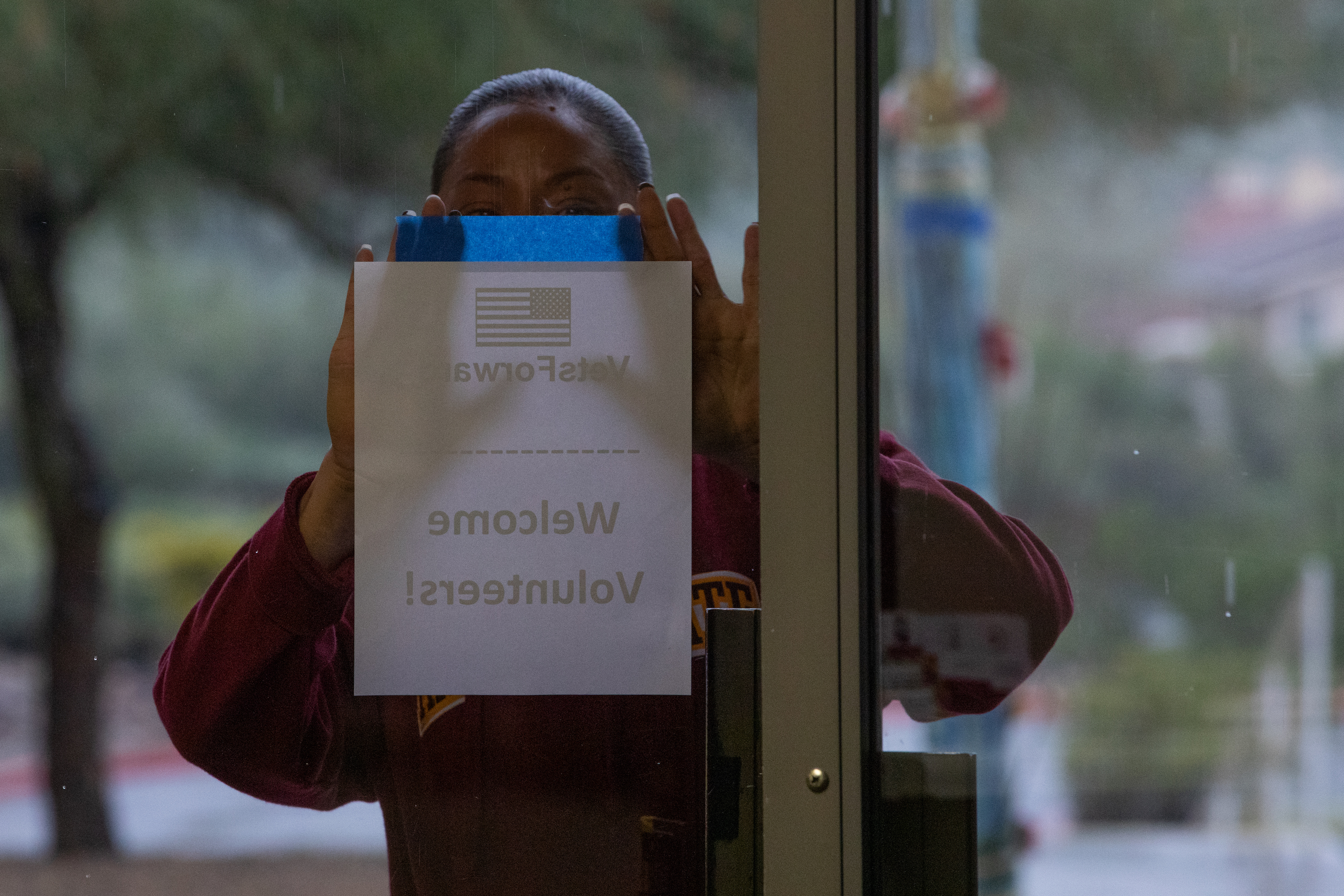 a woman putting a sign on the door to welcome volunteers